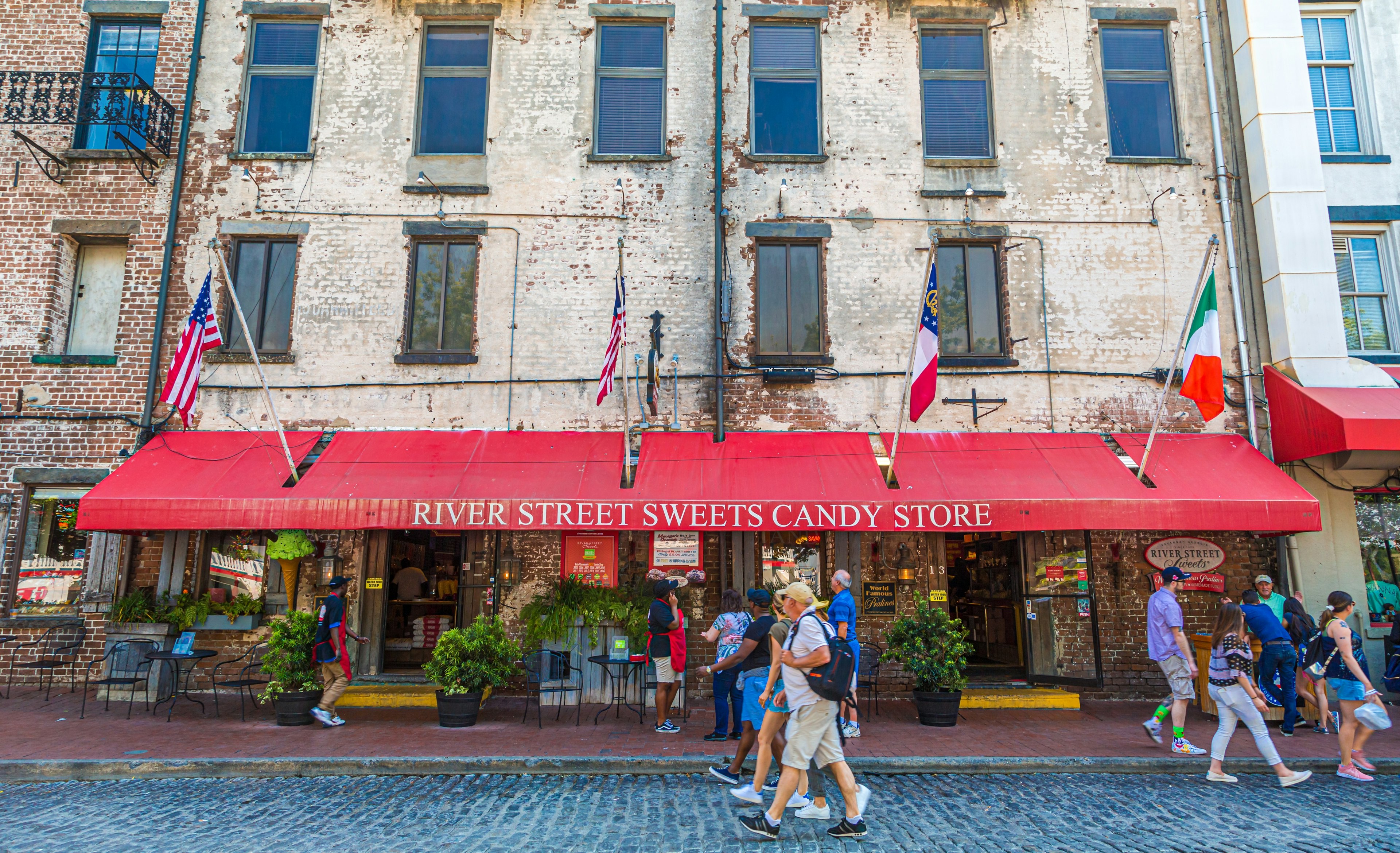 Passersby walk in front of River Street Sweets candy shop in Savannah.