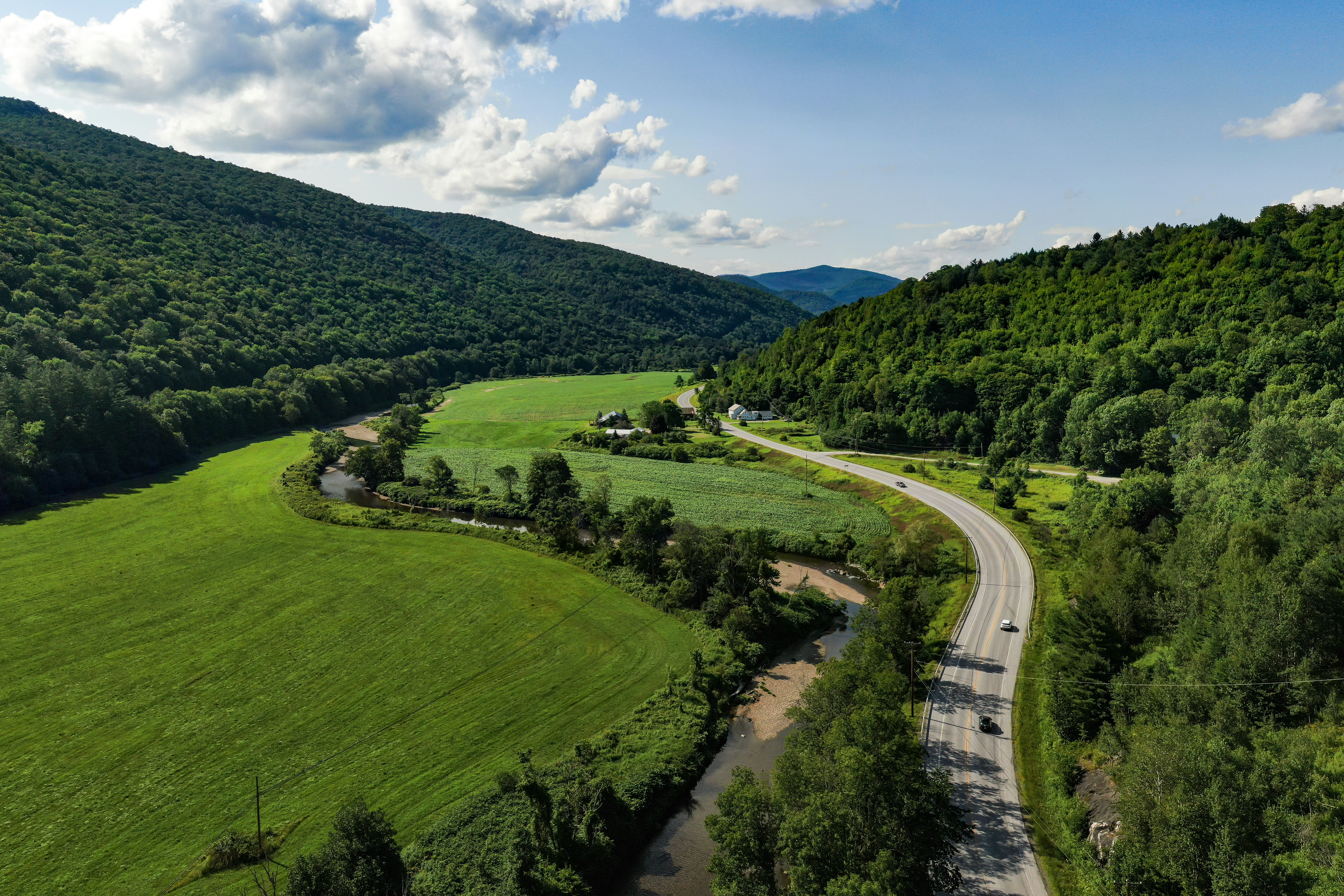 Aerial photography capturing the scenic route VT-100, guiding through Vermont. A historical road embraced by the green mountains and breathtaking spots made by mother nature.