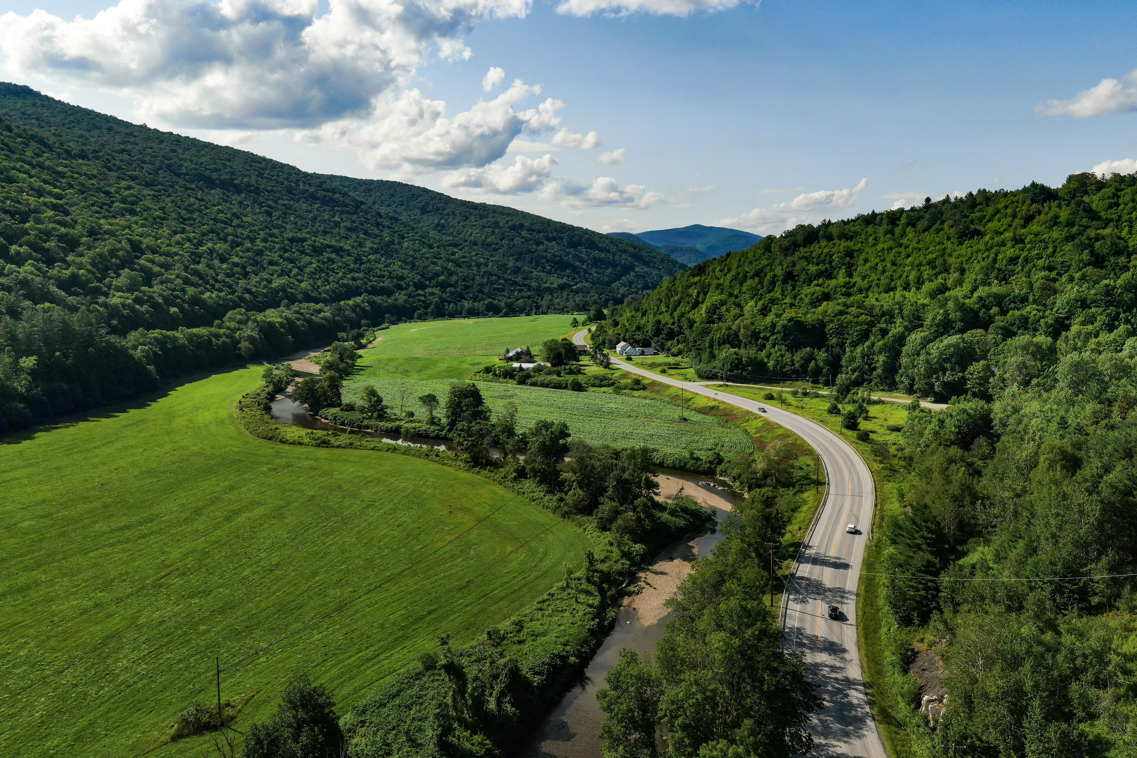 Aerial photography capturing the scenic route VT-100, guiding through Vermont. A historical road embraced by the green mountains and breathtaking spots made by mother nature.