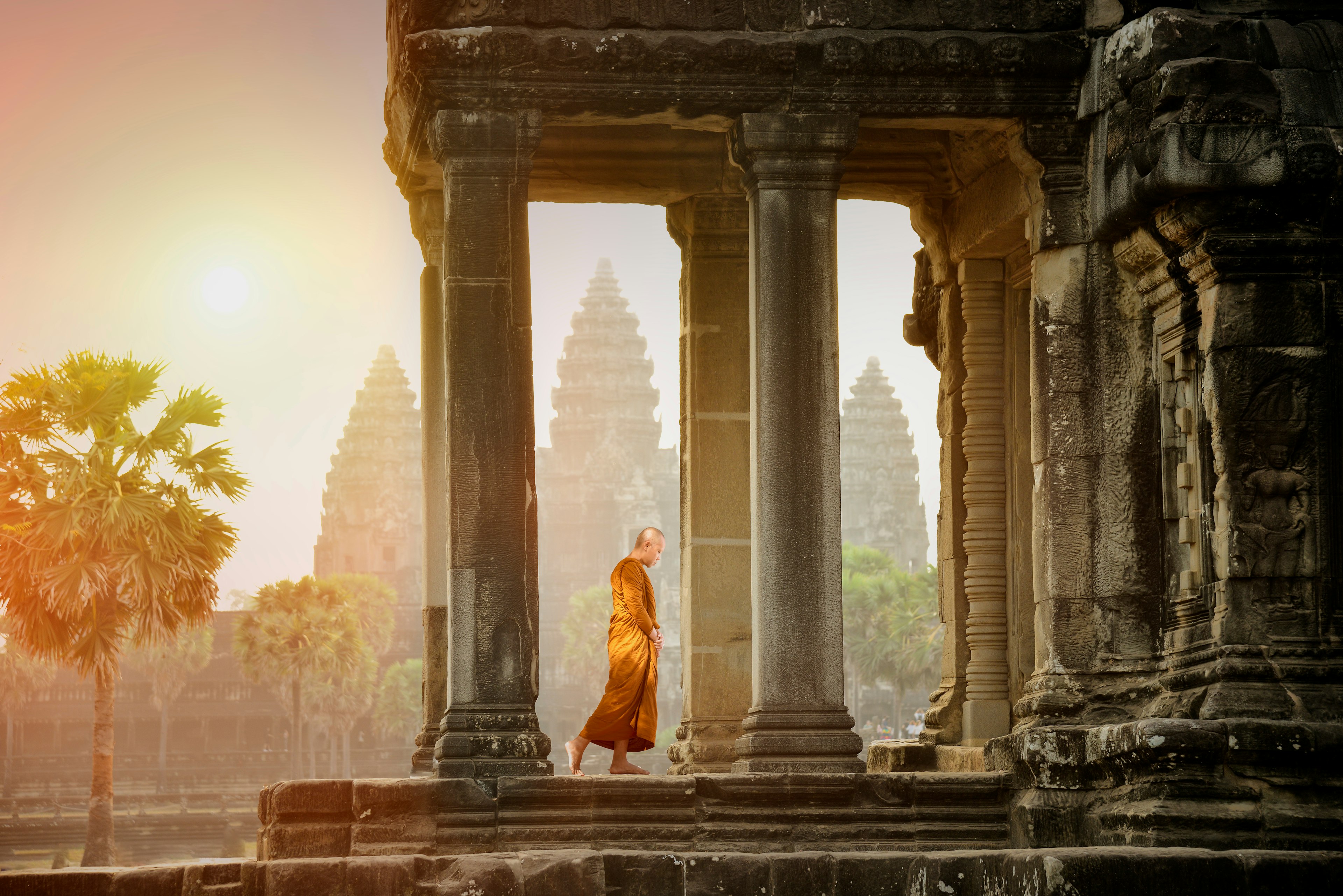 Monks walk into a shrine to see the stone carvings at sunset in Angkor Wat.