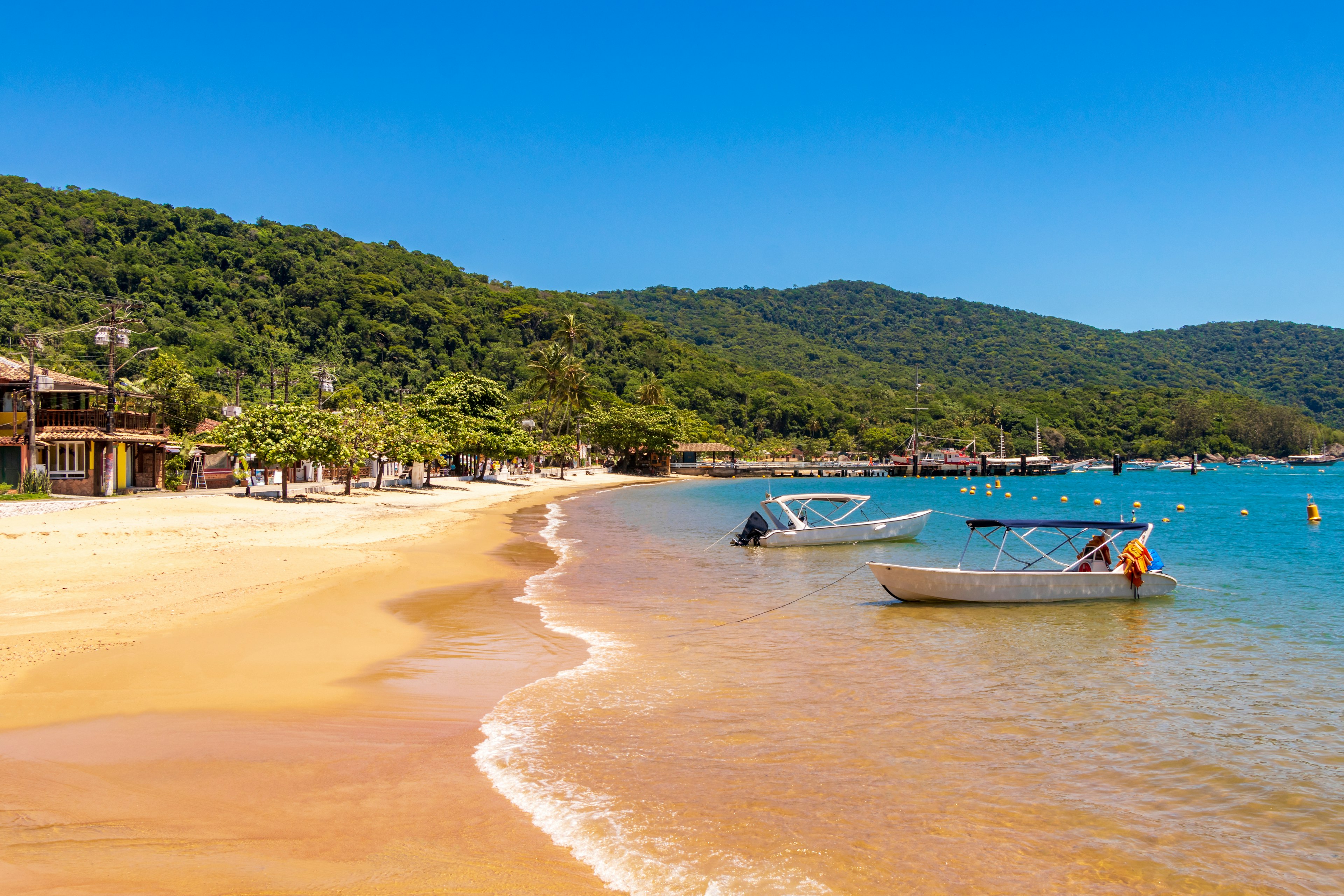 A peaceful golden-sand beach with small boats moored on the shore