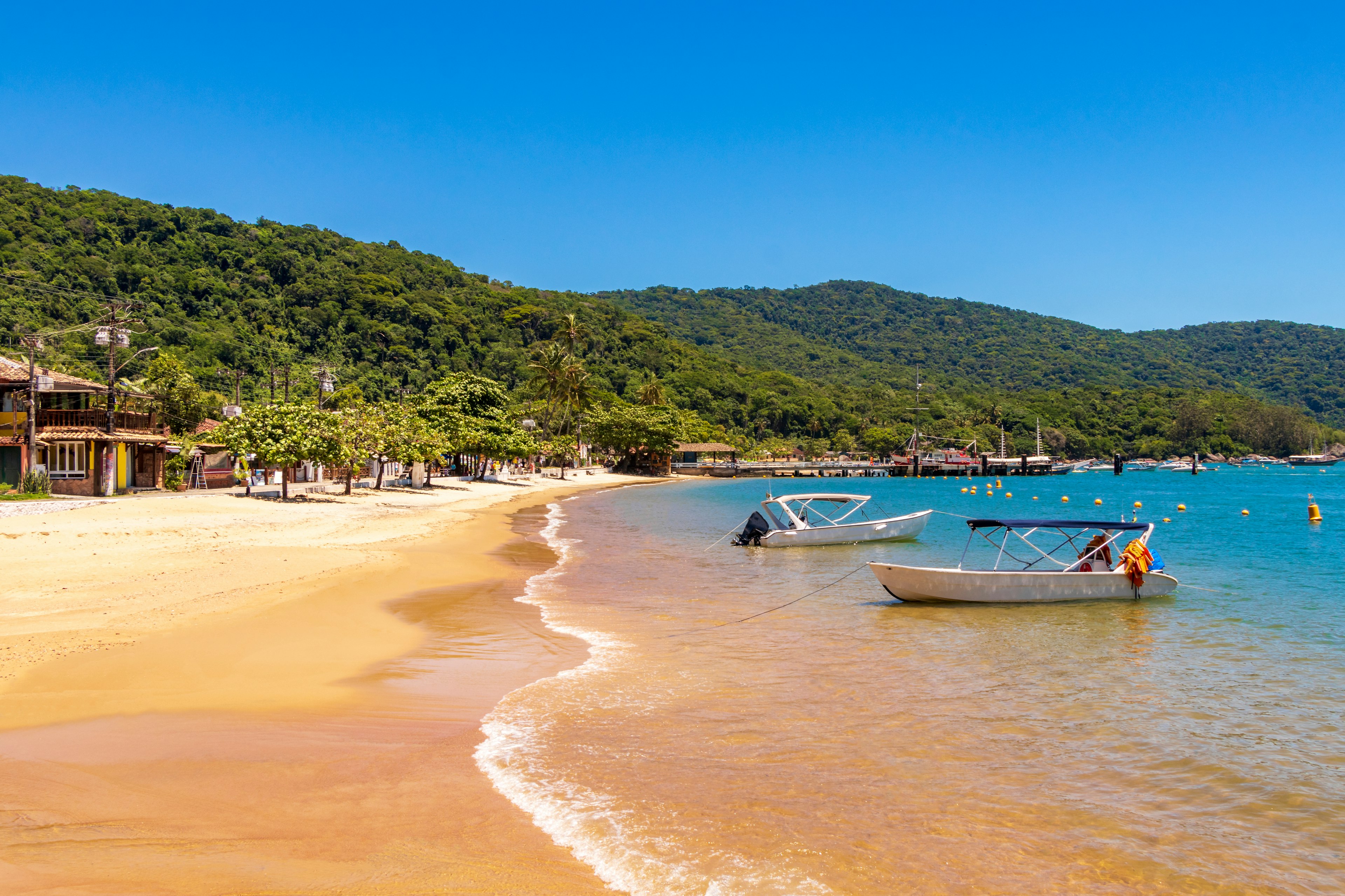 Playa de arena dorada tranquila con pequeños barcos anclados en la orilla