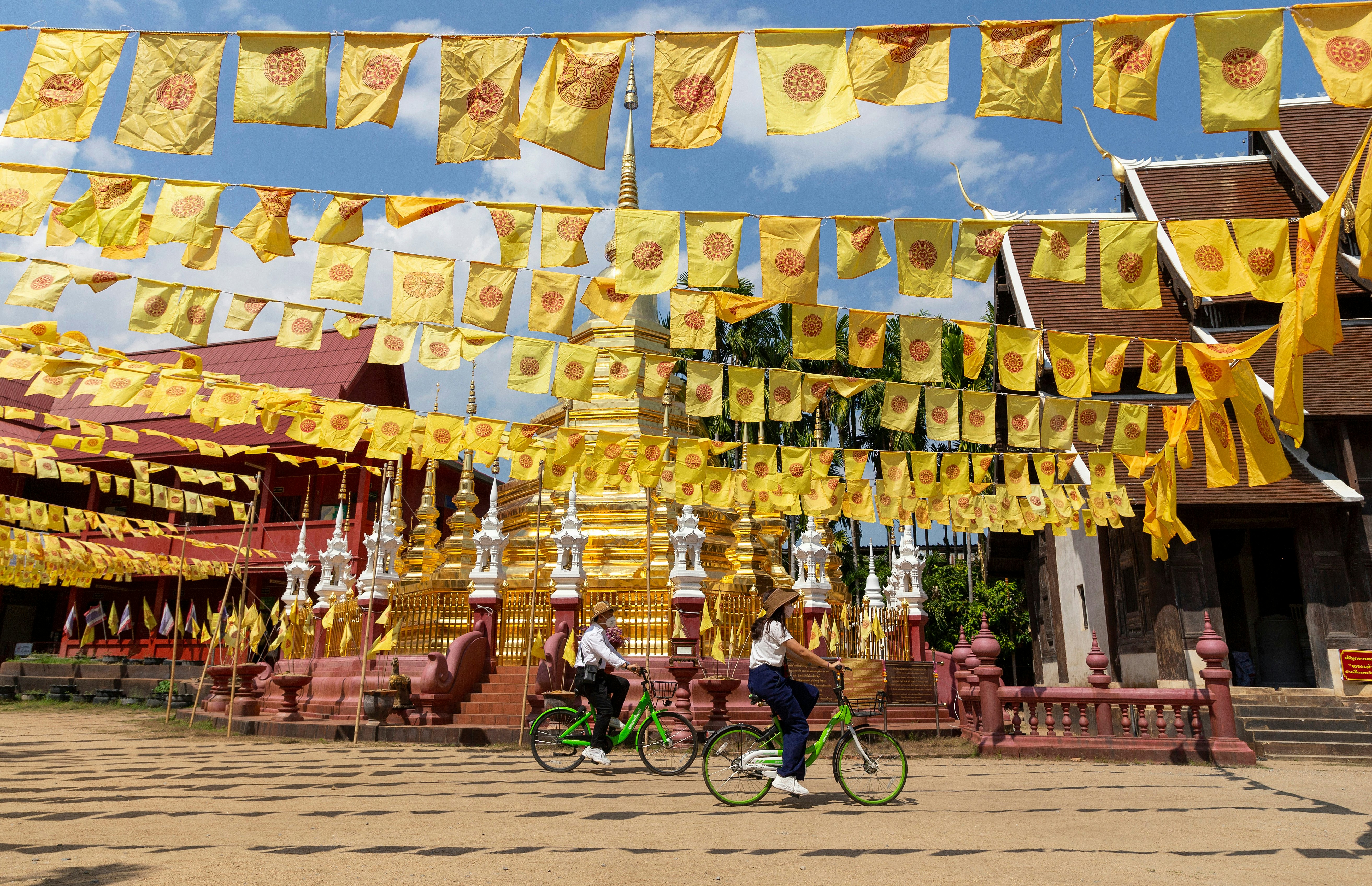 Chiang Mai, Thailand â€“ February 16, 2022: Visitors tourists wearing protective mask cycling past the pagoda in Wat Phan Tao Temple, in Chiang Mai, Thailand. after restarted 'Test and Go' program  License Type: media  Download Time: 2023-11-13T08:30:10.000Z  User: lonelyplanetmedia  Is Editorial: Yes  purchase_order: