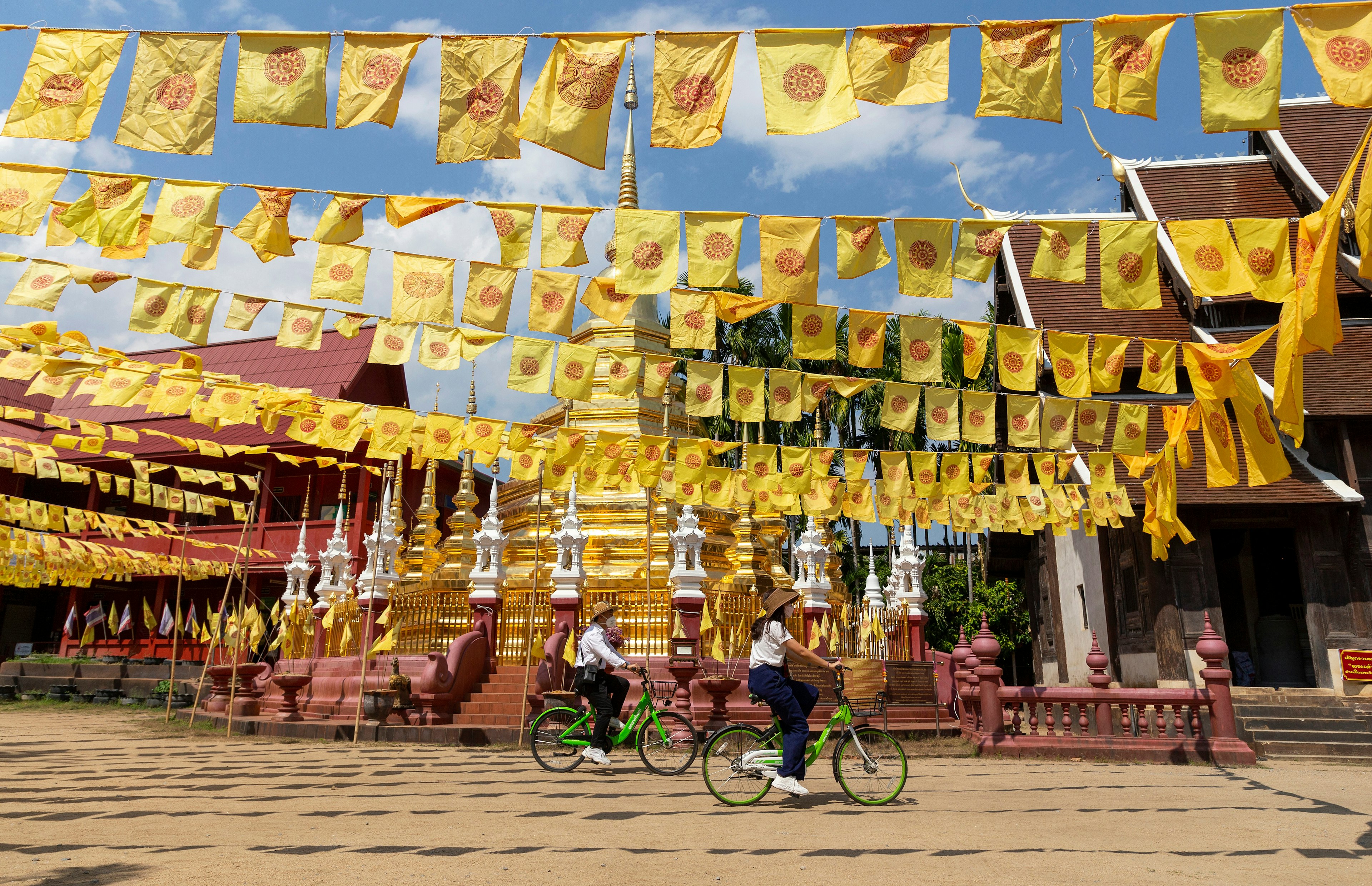 Chiang Mai, Thailand – February 16, 2022: Visitors tourists wearing protective mask cycling past the pagoda in Wat Phan Tao Temple, in Chiang Mai, Thailand. after restarted 'Test and Go' program License Type: media Download Time: 2023-11-13T08:30:10.000Z User: lonelyplanetmedia Is Editorial: Yes purchase_order: