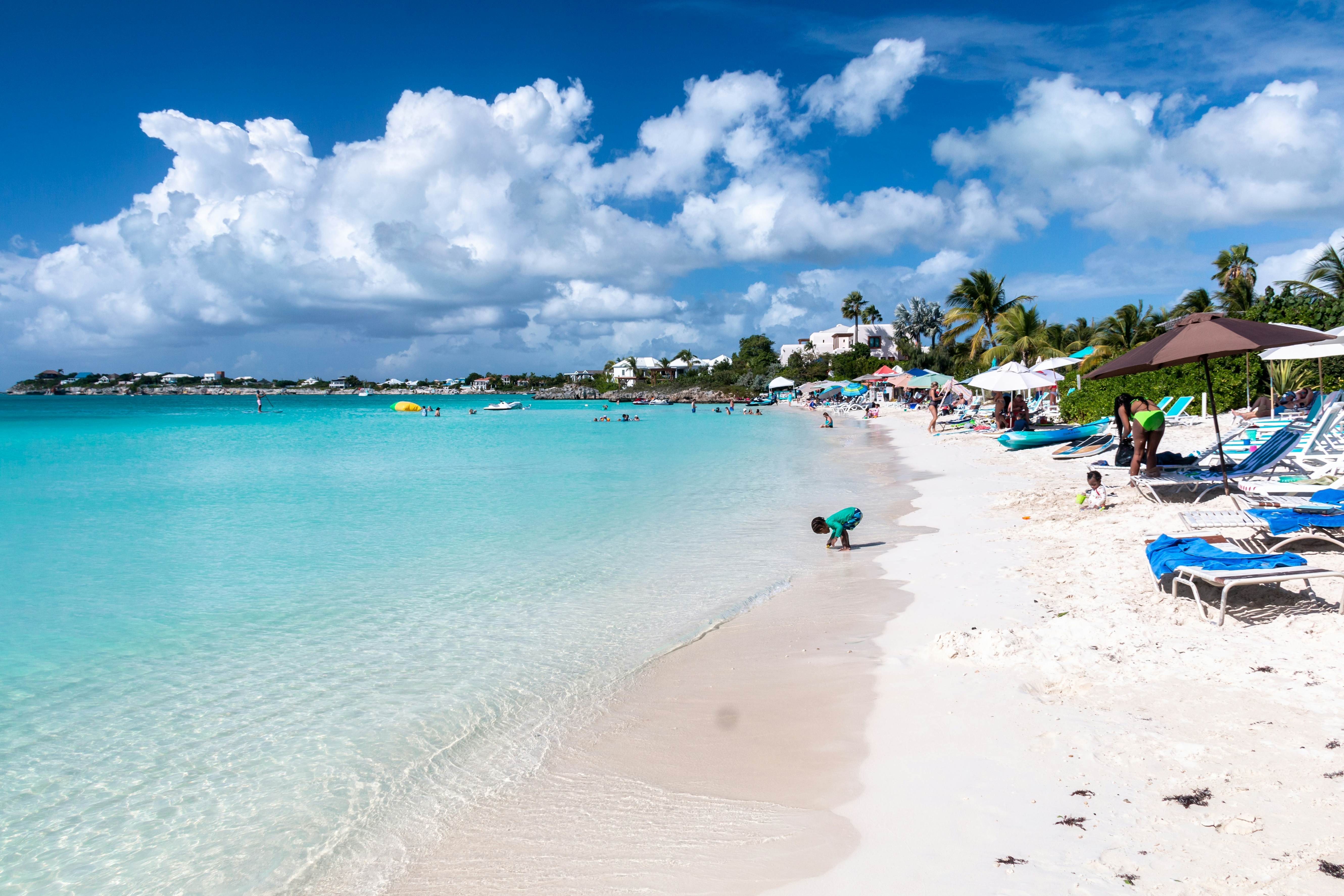 Families enjoy the white sand and crystal clear Caribbean waters of Sapodilla Bay Beach in the Turks and Caicos Islands.