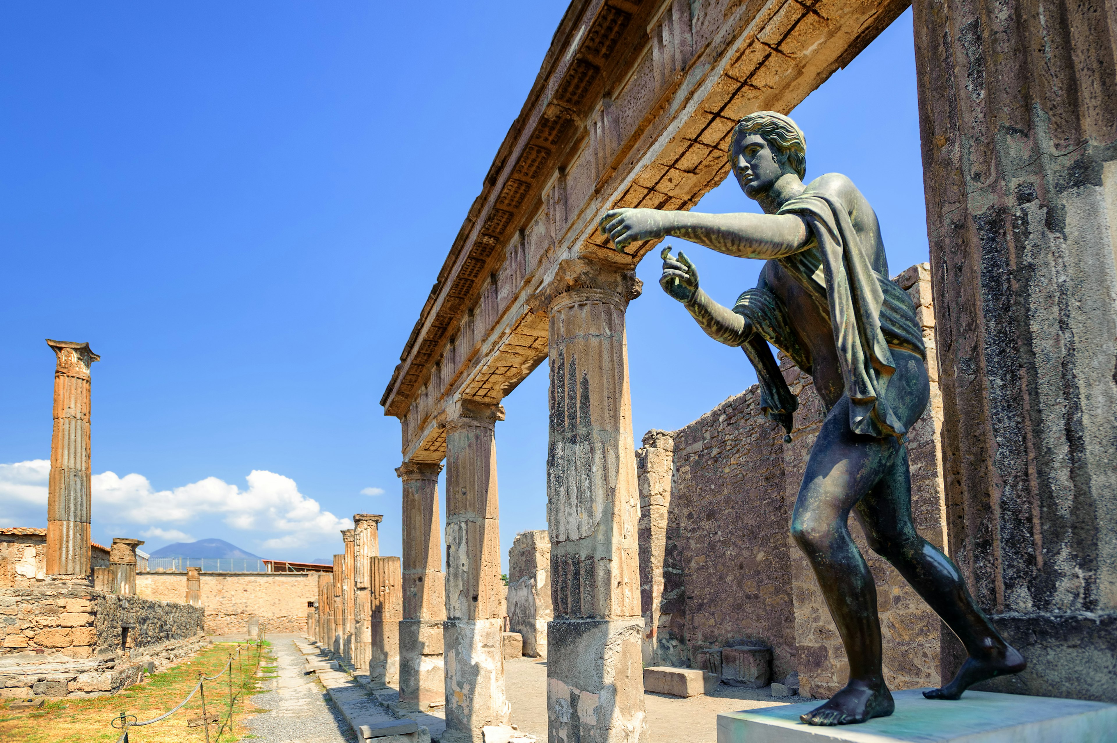 A statue of Apollo reaches forward within the ruins of a temple in Pompeii.