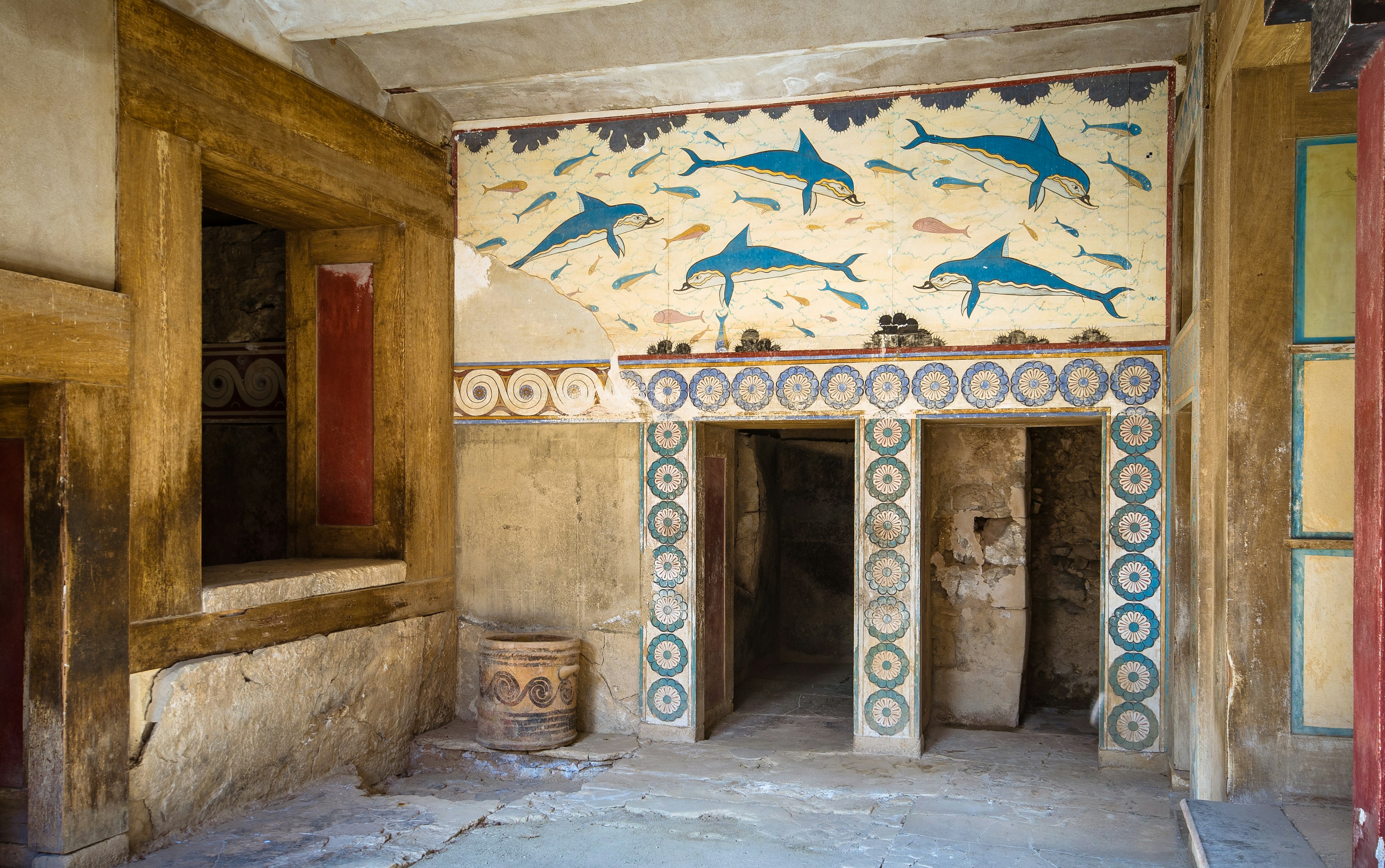 Dolphins and ornate designs are painting on a fresco on an ancient building in Greece.