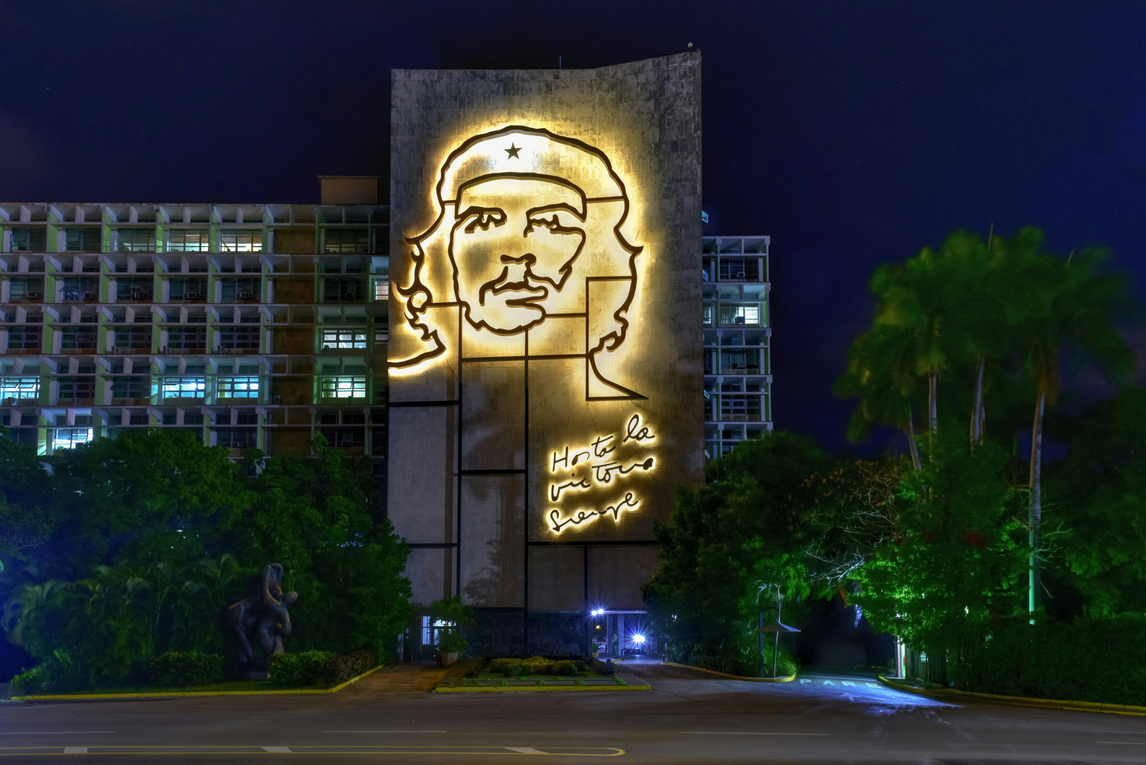 A vast portrait of Che Guevara on the exterior wall of a goverment building lit up at night