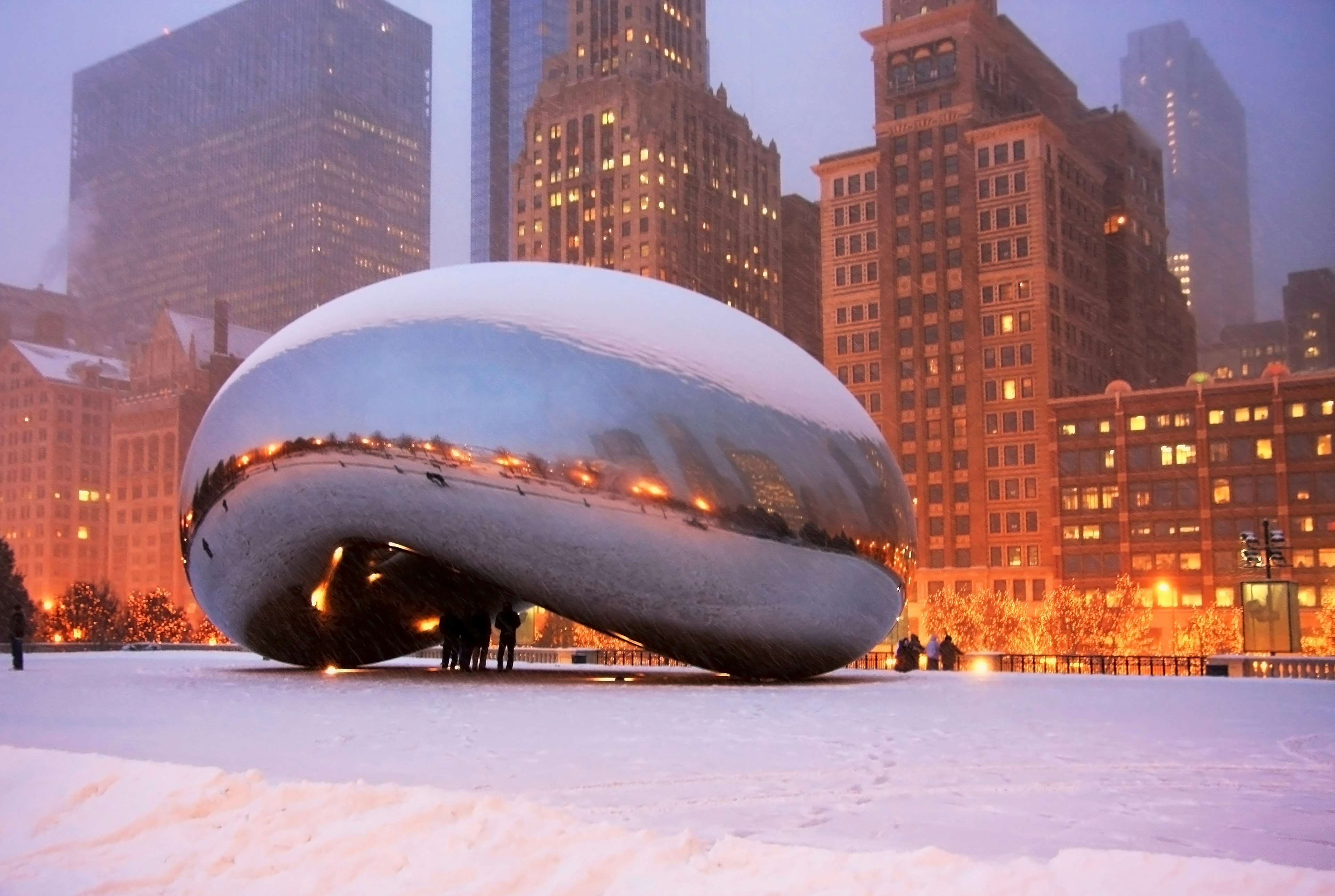 Beautiful snowy winter night in the center of Chicago, with people sheltering under the Bean sculpture.