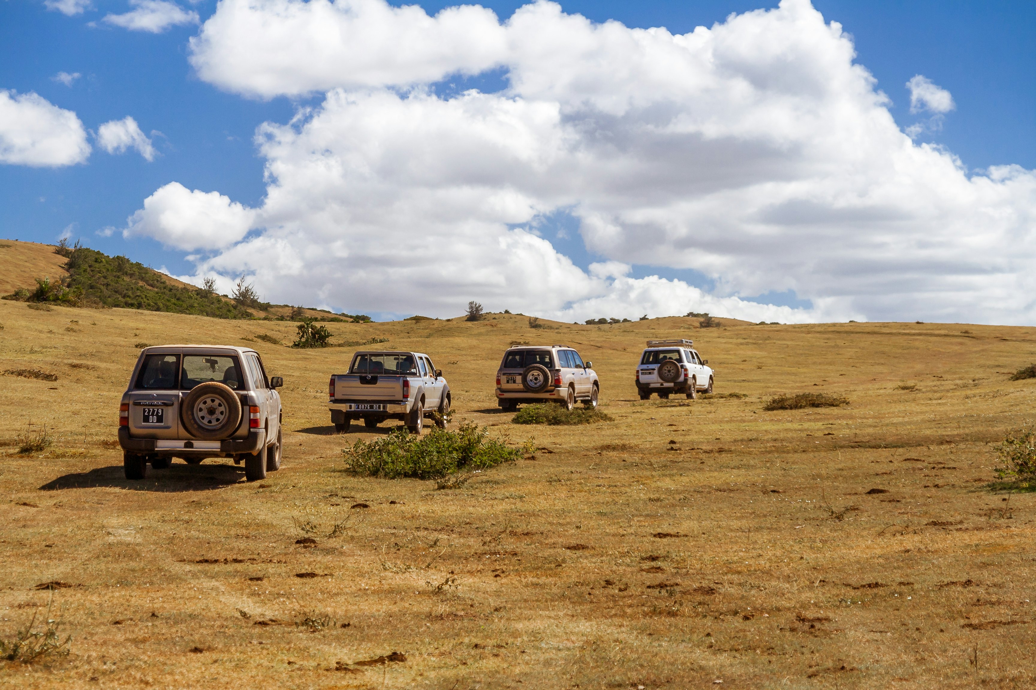 Four vehicles off-road in a field of grass near Vohemar in Eastern Madagascar.