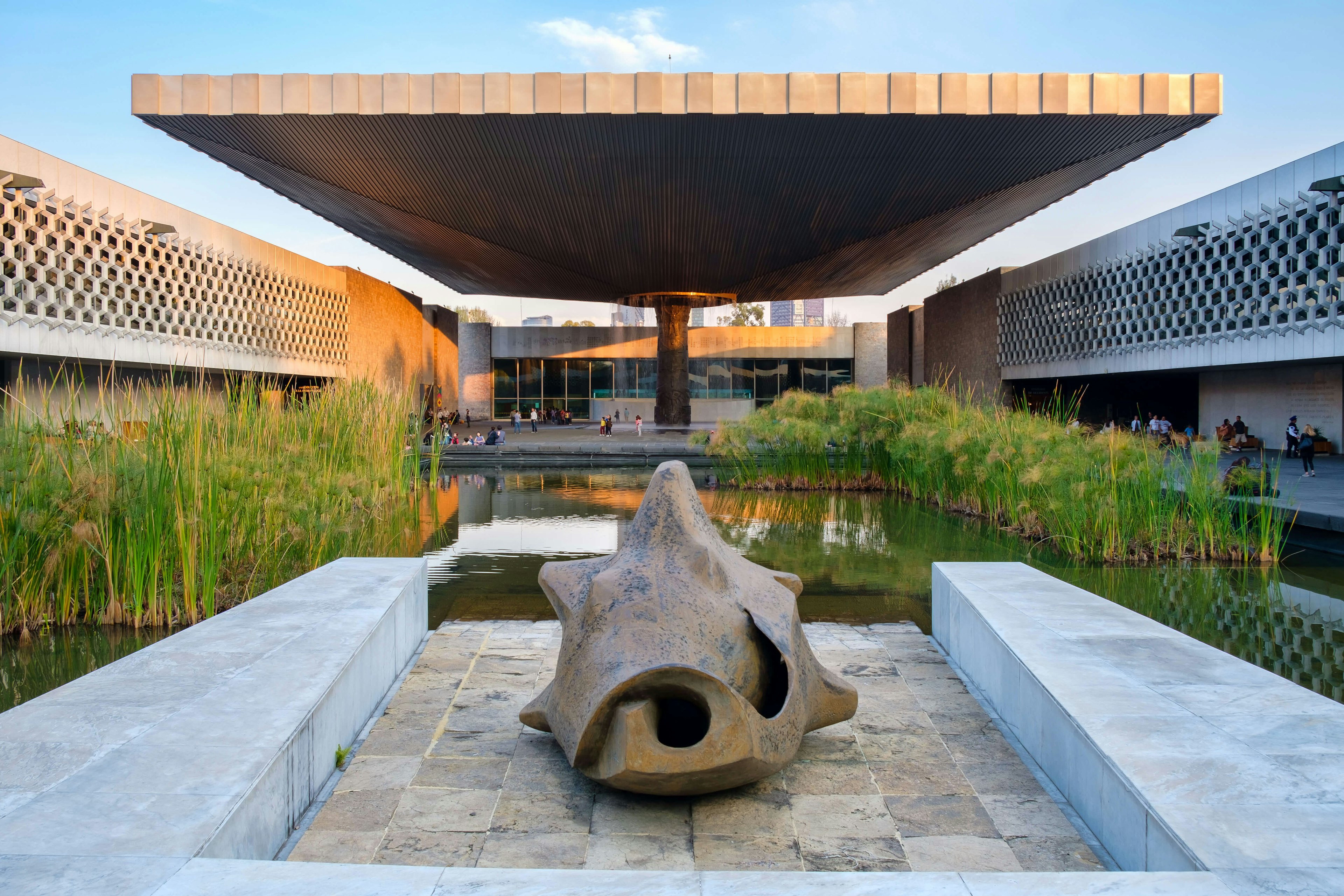 People outside a museum building with ponds, sculptures and a fountain