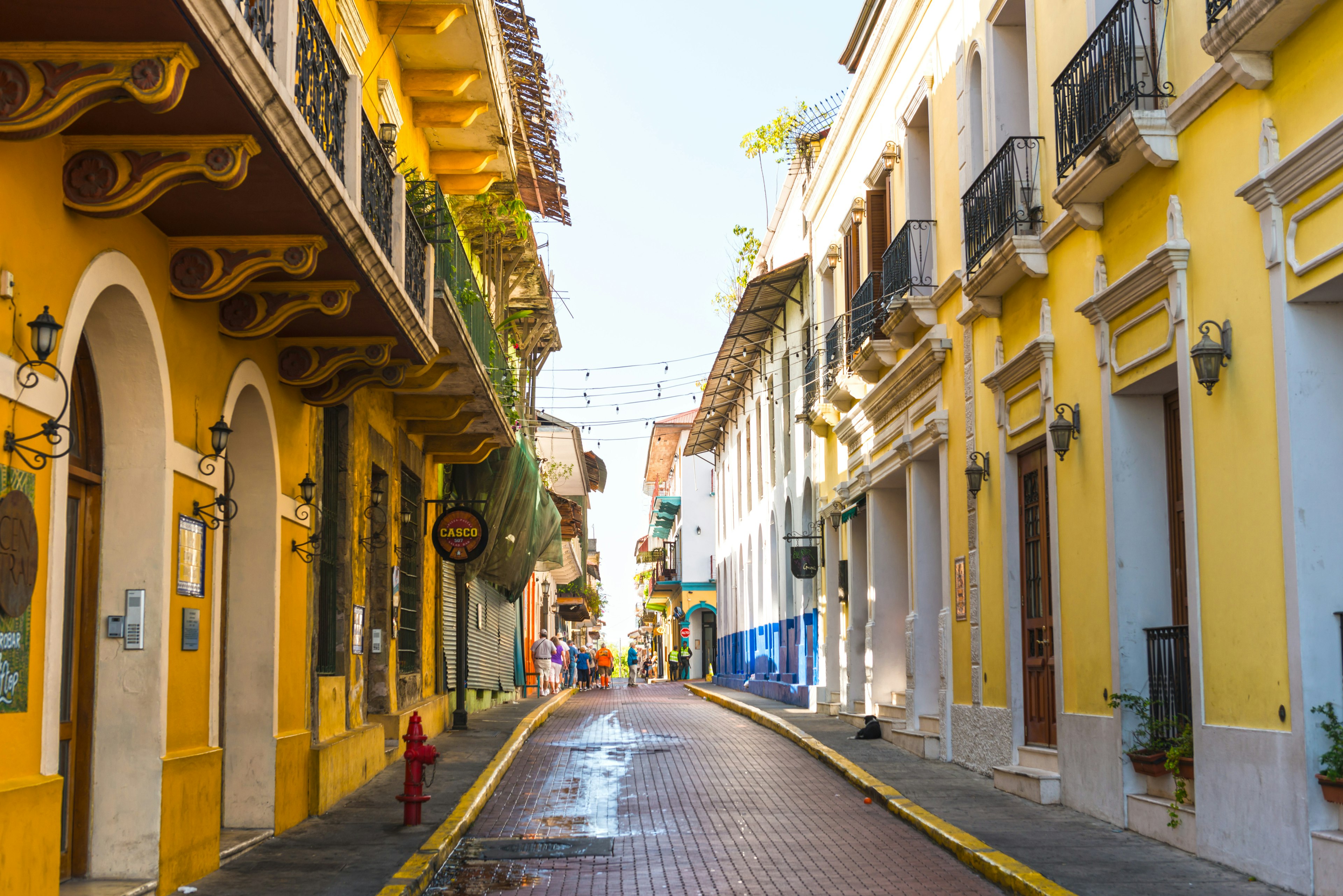 Casco Viejo street in an old part of Panama City with small group of people walking in distance early in the morning.