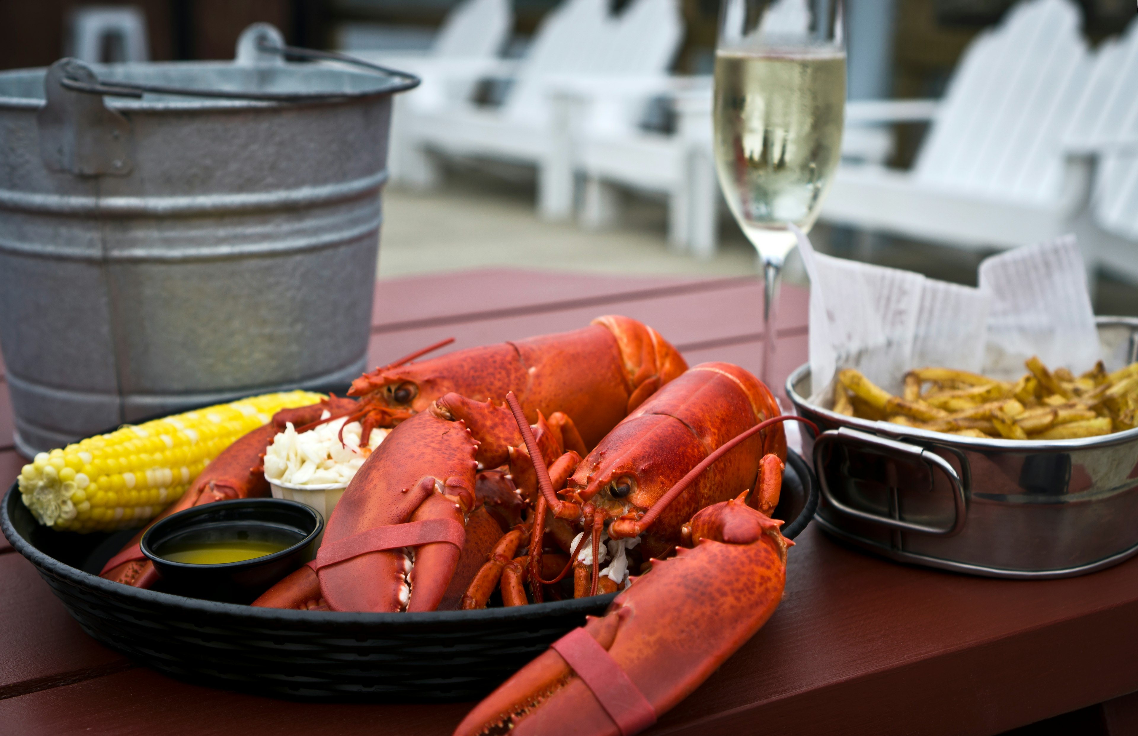 Boiled twin lobster with drawn butter, coleslaw, corn on the cob and French fries, a traditional meal of vacationers in the Coastal Maine. Summer feast in New England.