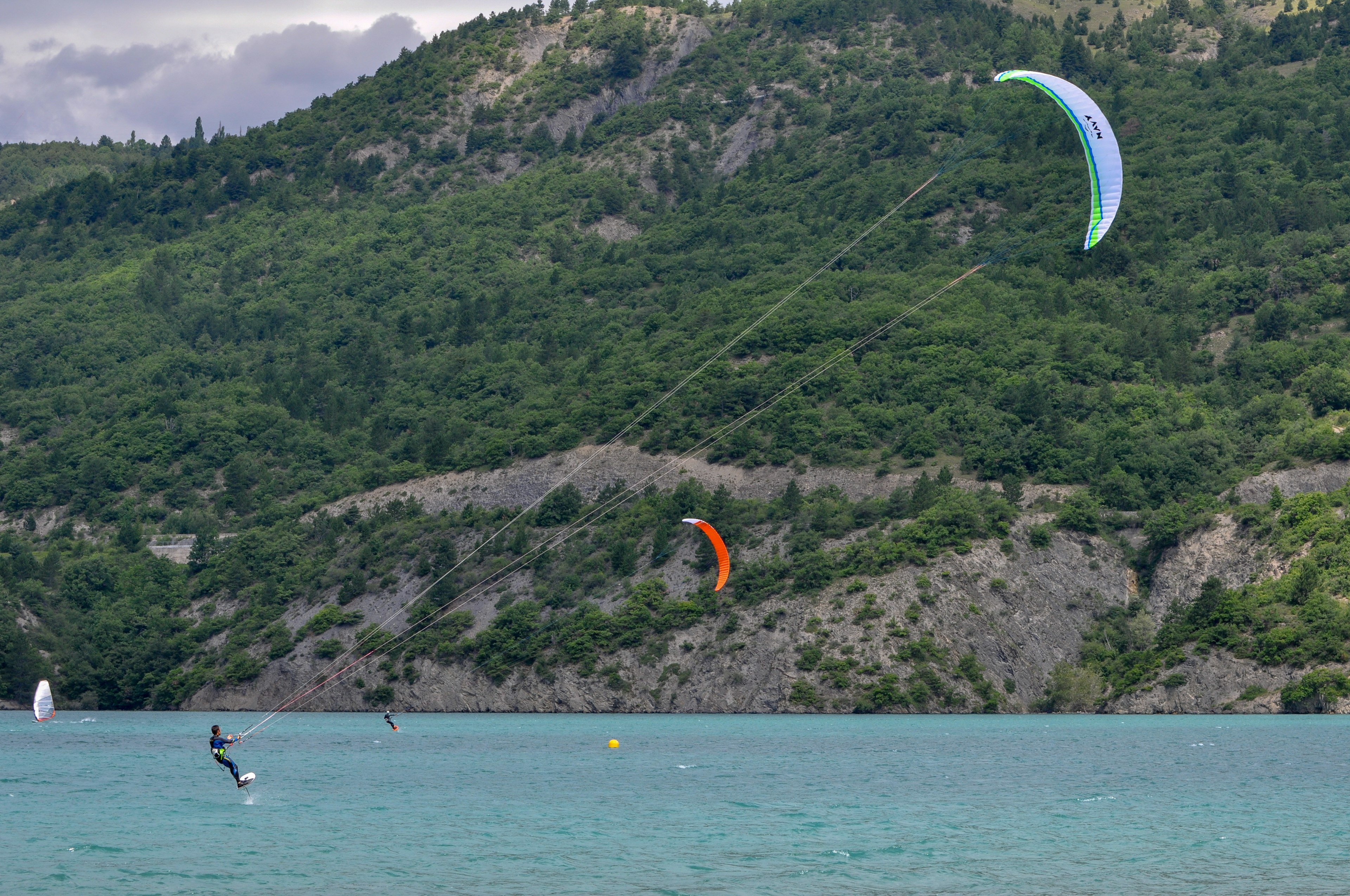 Kitefoilers float above the water on their hydrofoils as their kites lift them into the sky