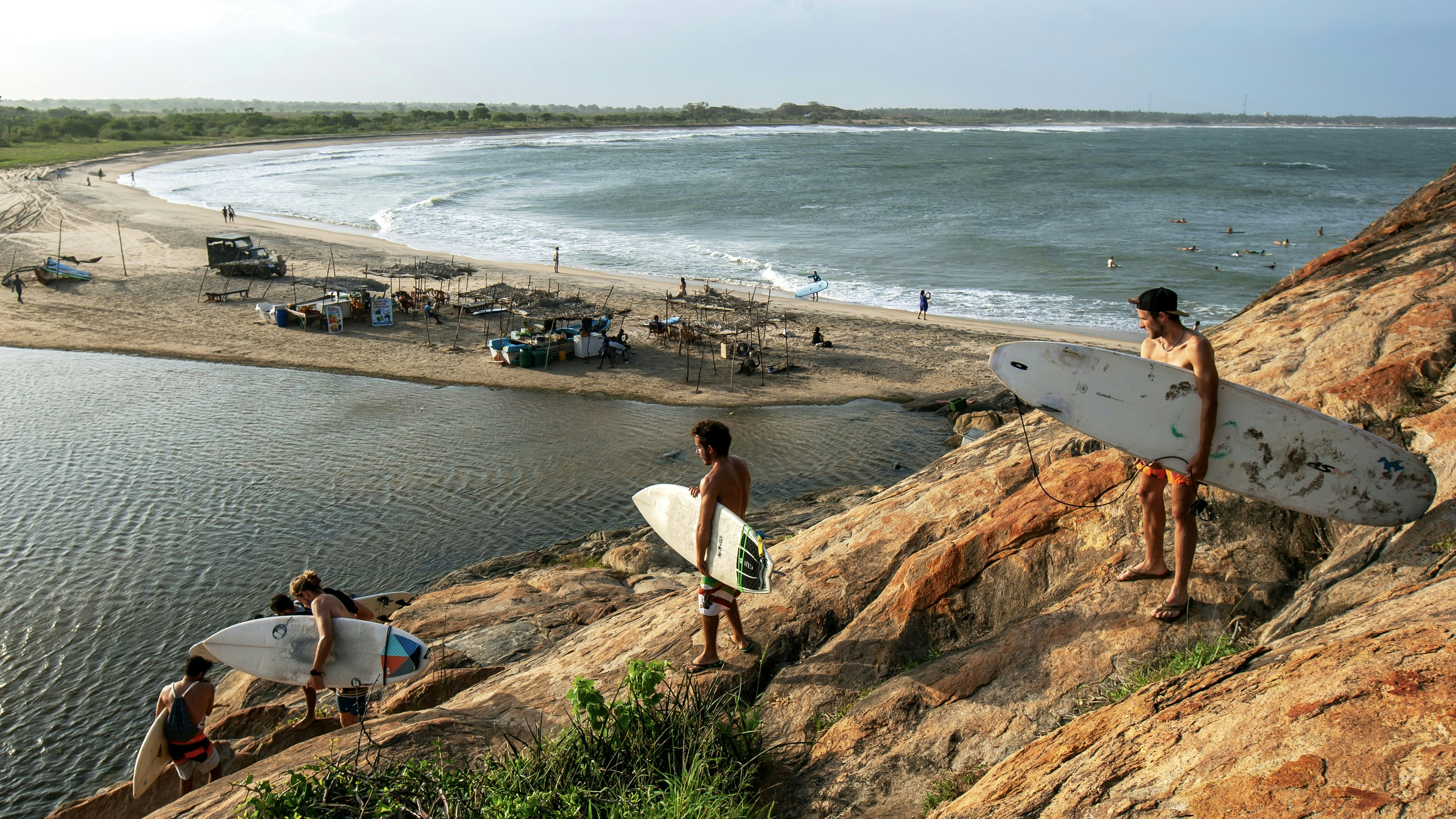 A group of surfers climb down Elephant Rock towards the beach for a surfing session.