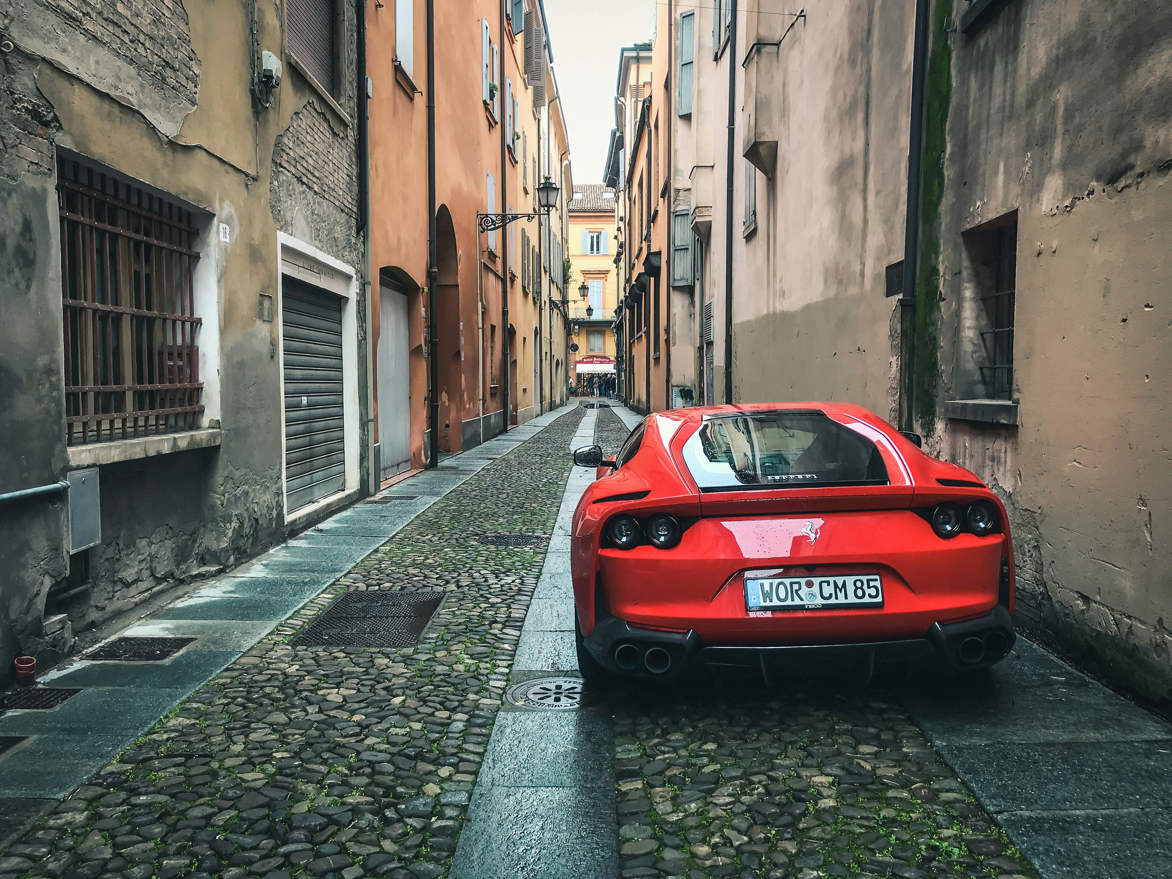 A Ferrari 812 Superfast parked in an alley in the historic center of Modena, Italy.