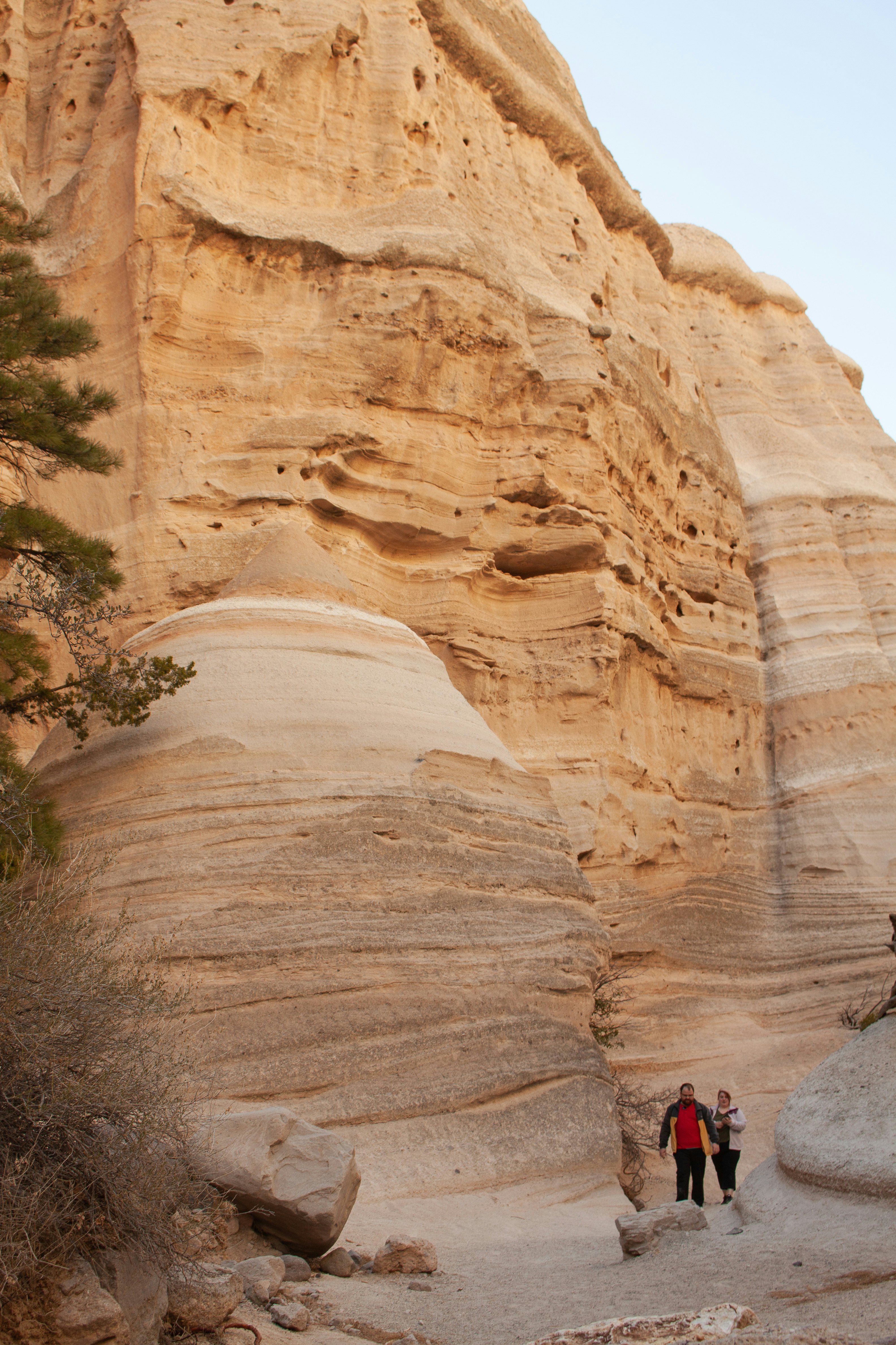 Hikers walk through an arid desert canyon with steep walls in New Mexico