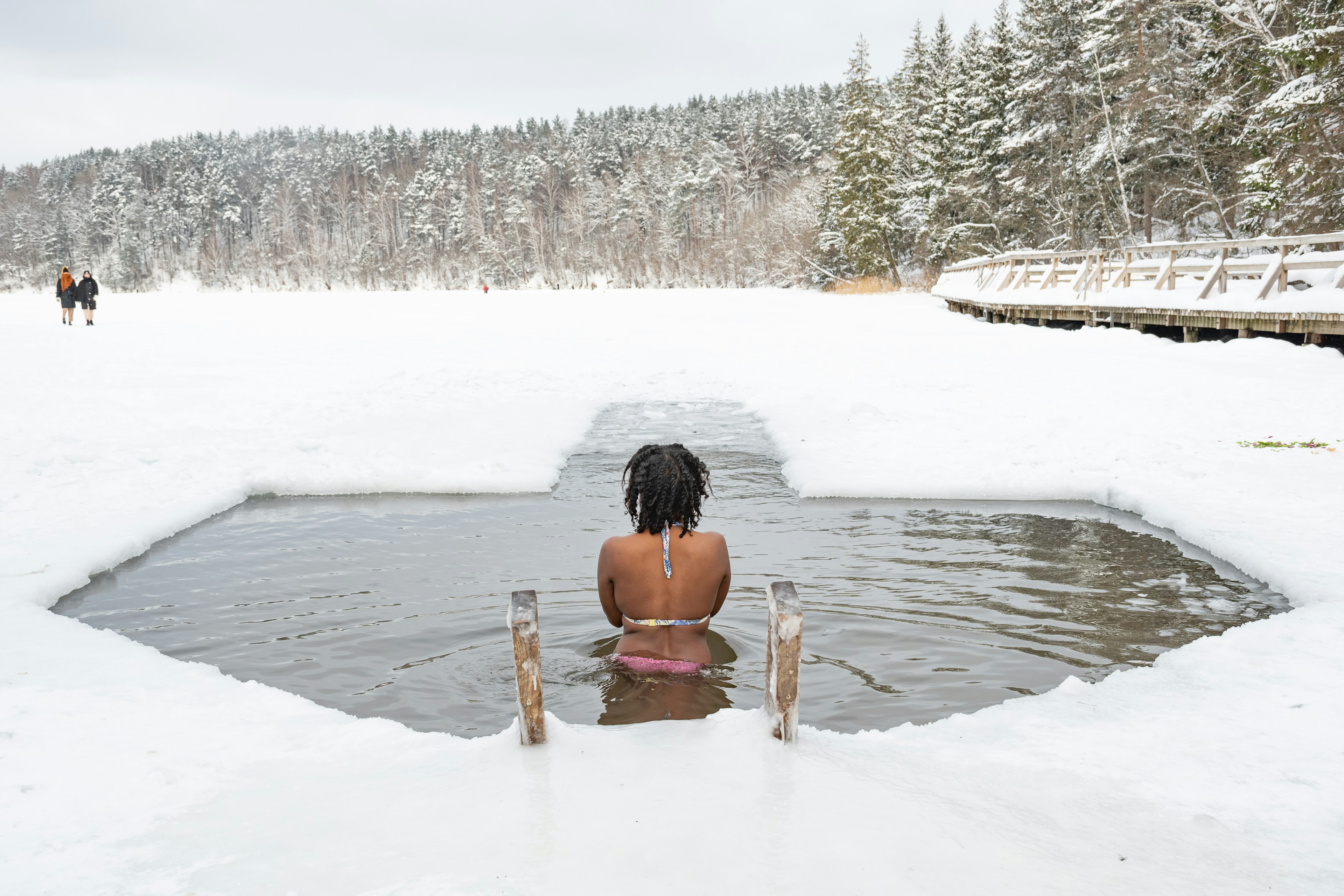 A woman in an ice hole surrounded by snow and woodland