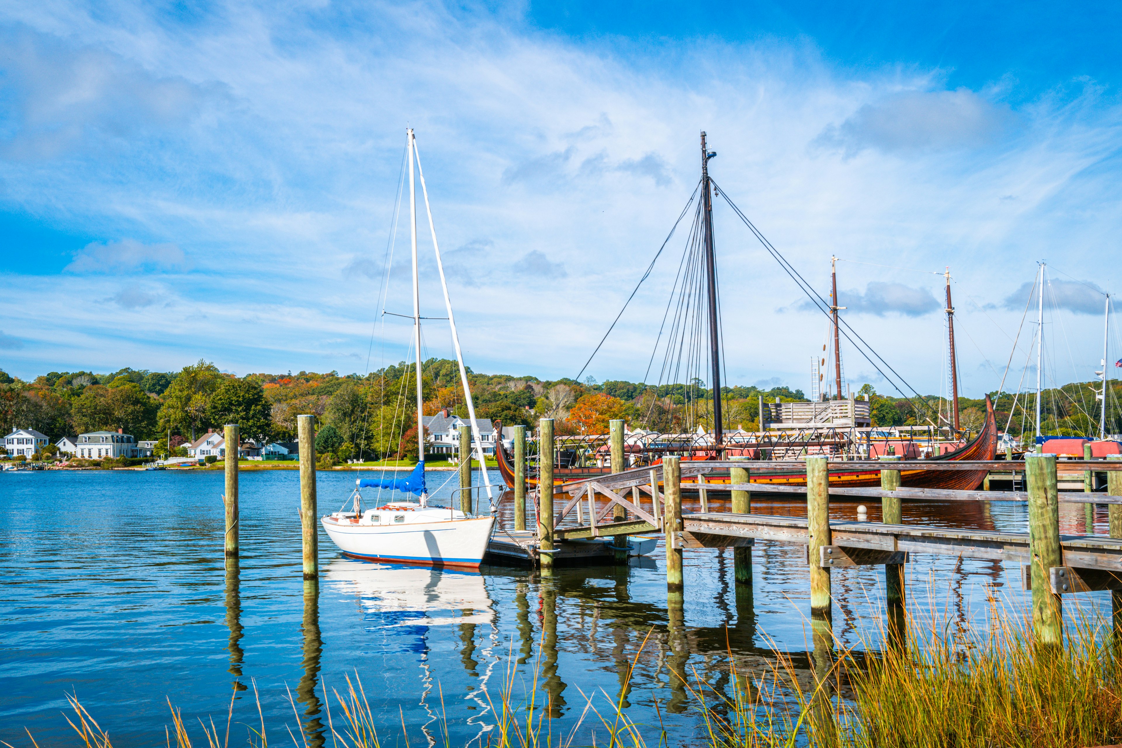 Commercial dock with moored white boat and sailing ship in Mystic, Connecticut.