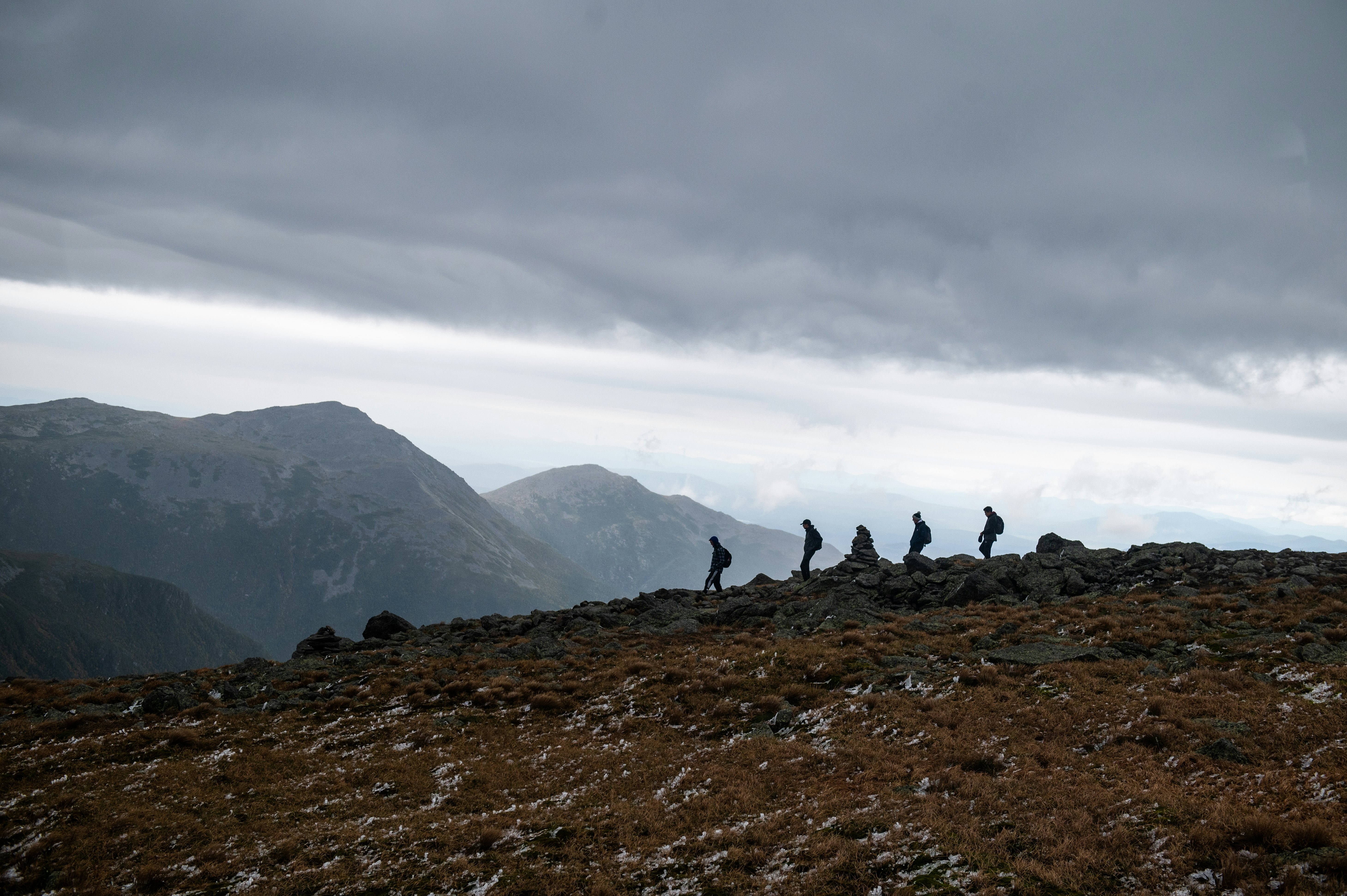 Hikers make their way down a rocky mountain landscape