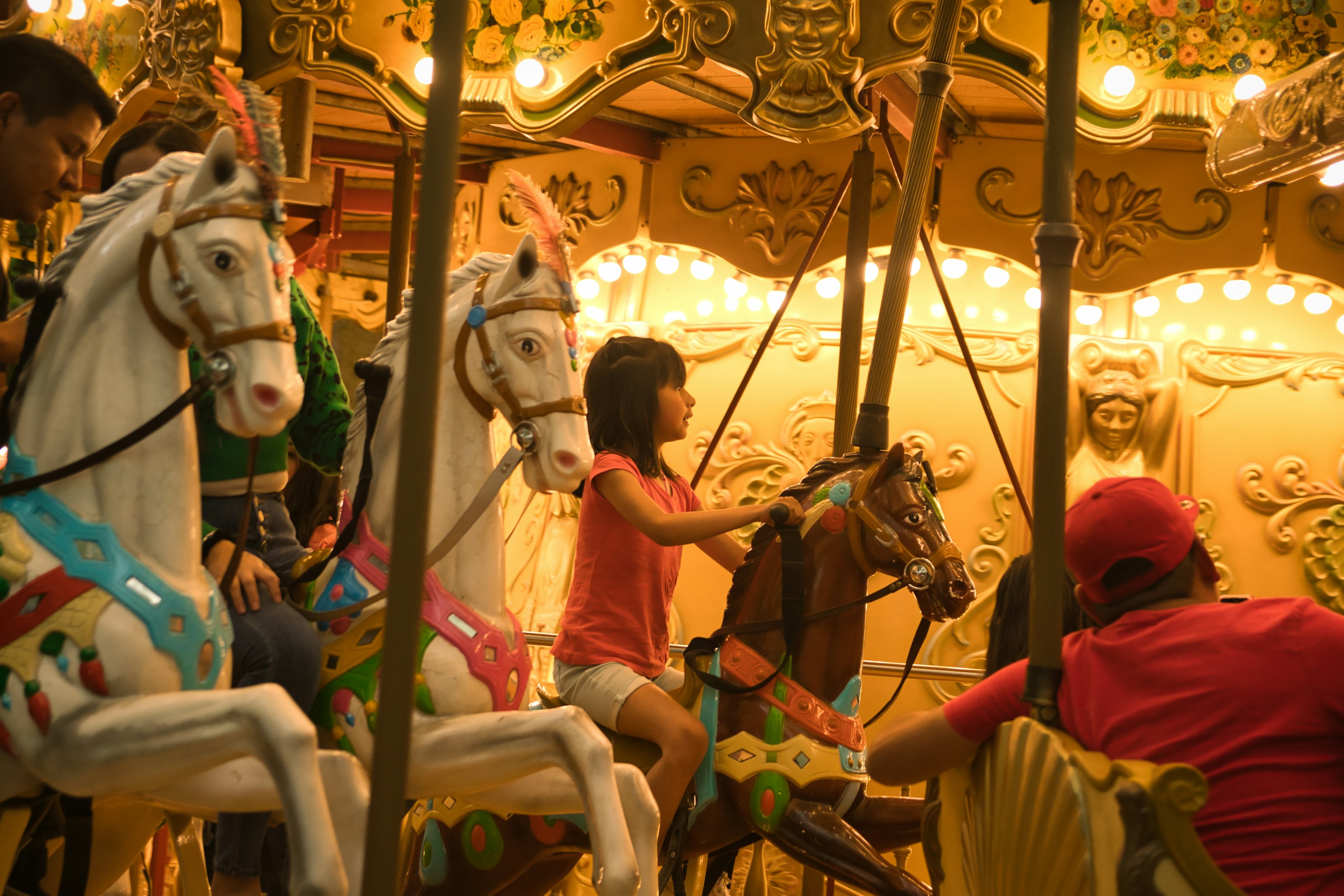 A young girl rides on a horse on a carousel