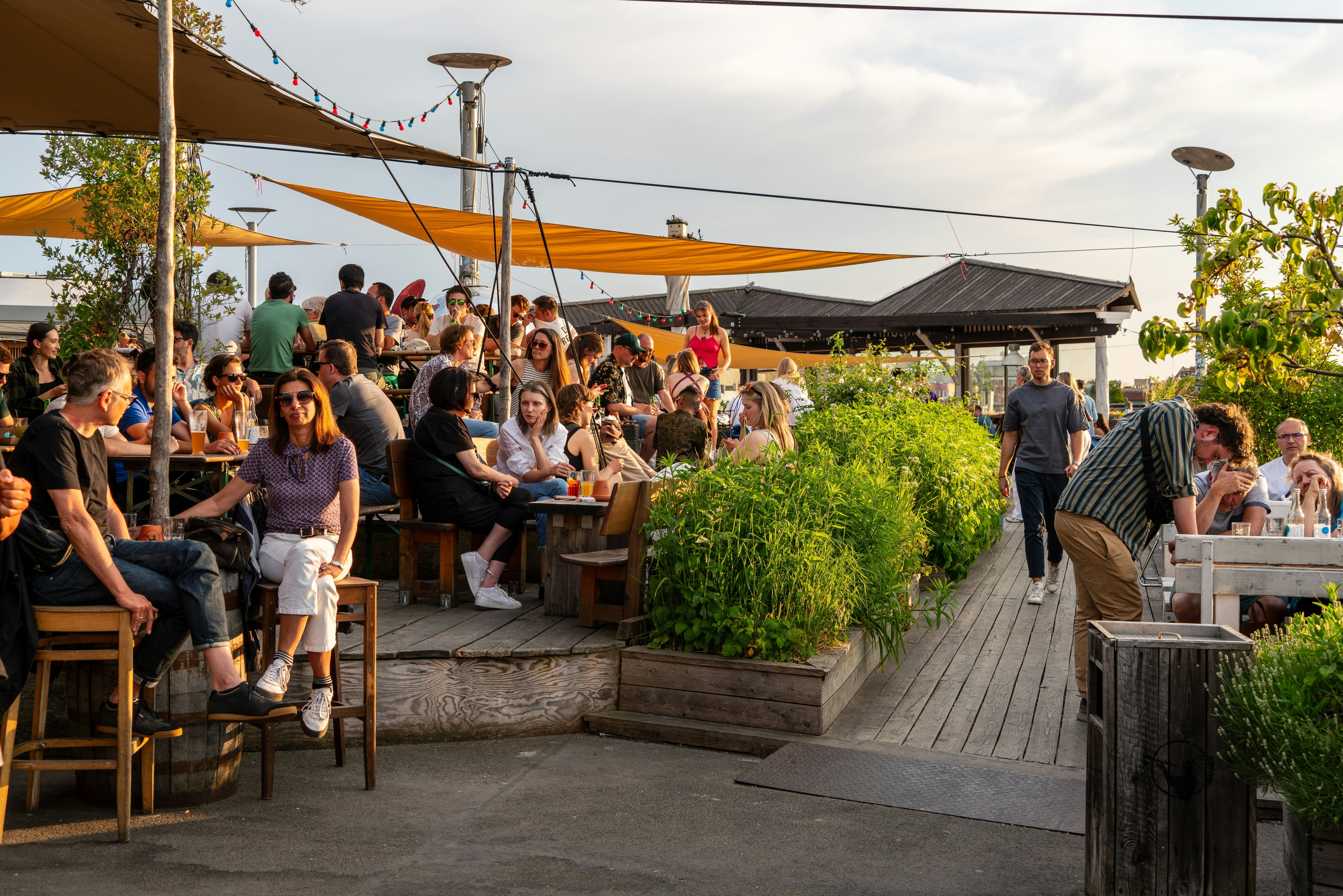 A rooftop bar with lots of people enjoying drinks in the sunshine
