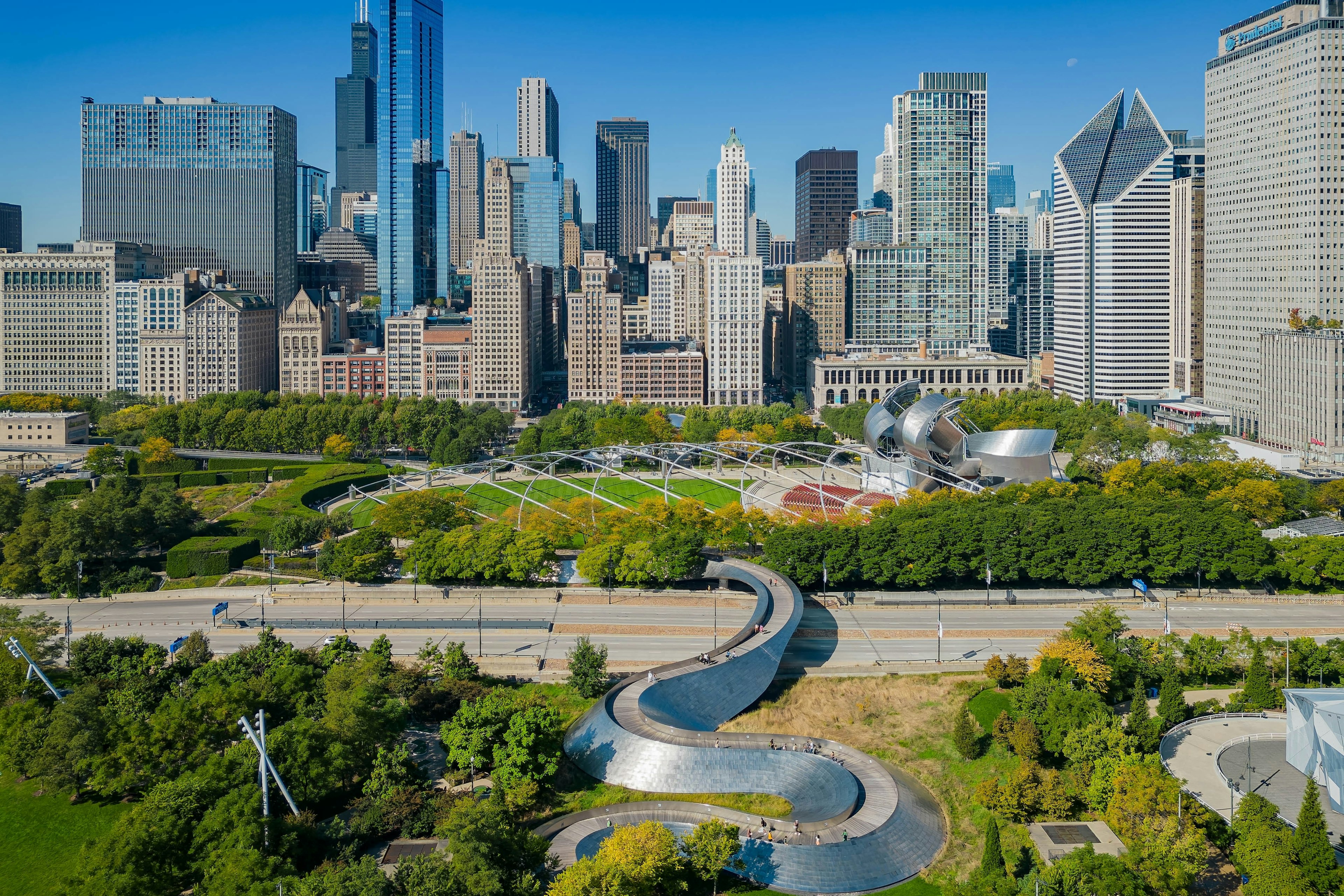 Aerial view of the BP Bridge in Millennium Park in Chicago with skyscrapers behind.