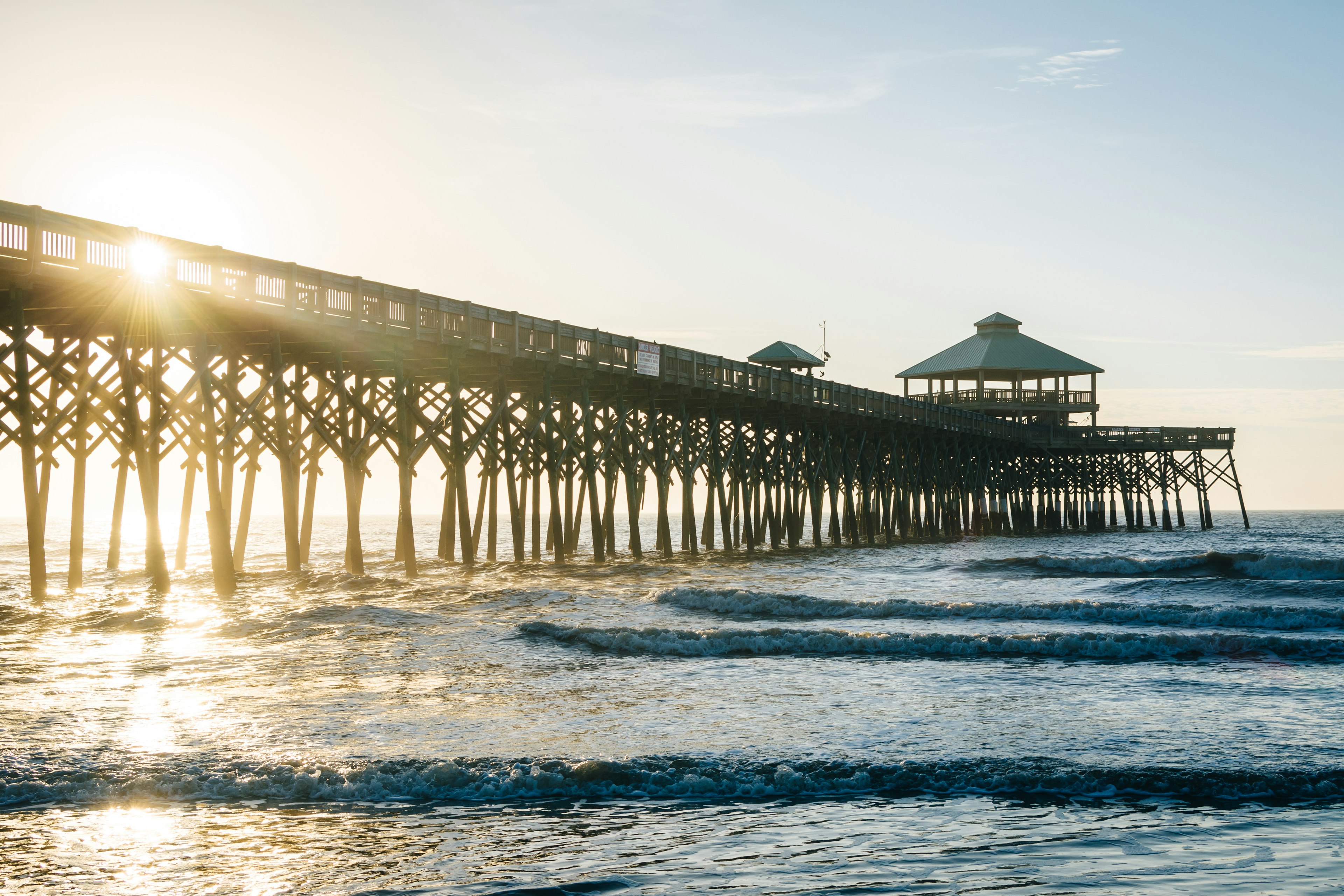 Waves in the Atlantic Ocean and the pier at sunrise, in Folly Beach, South Carolina