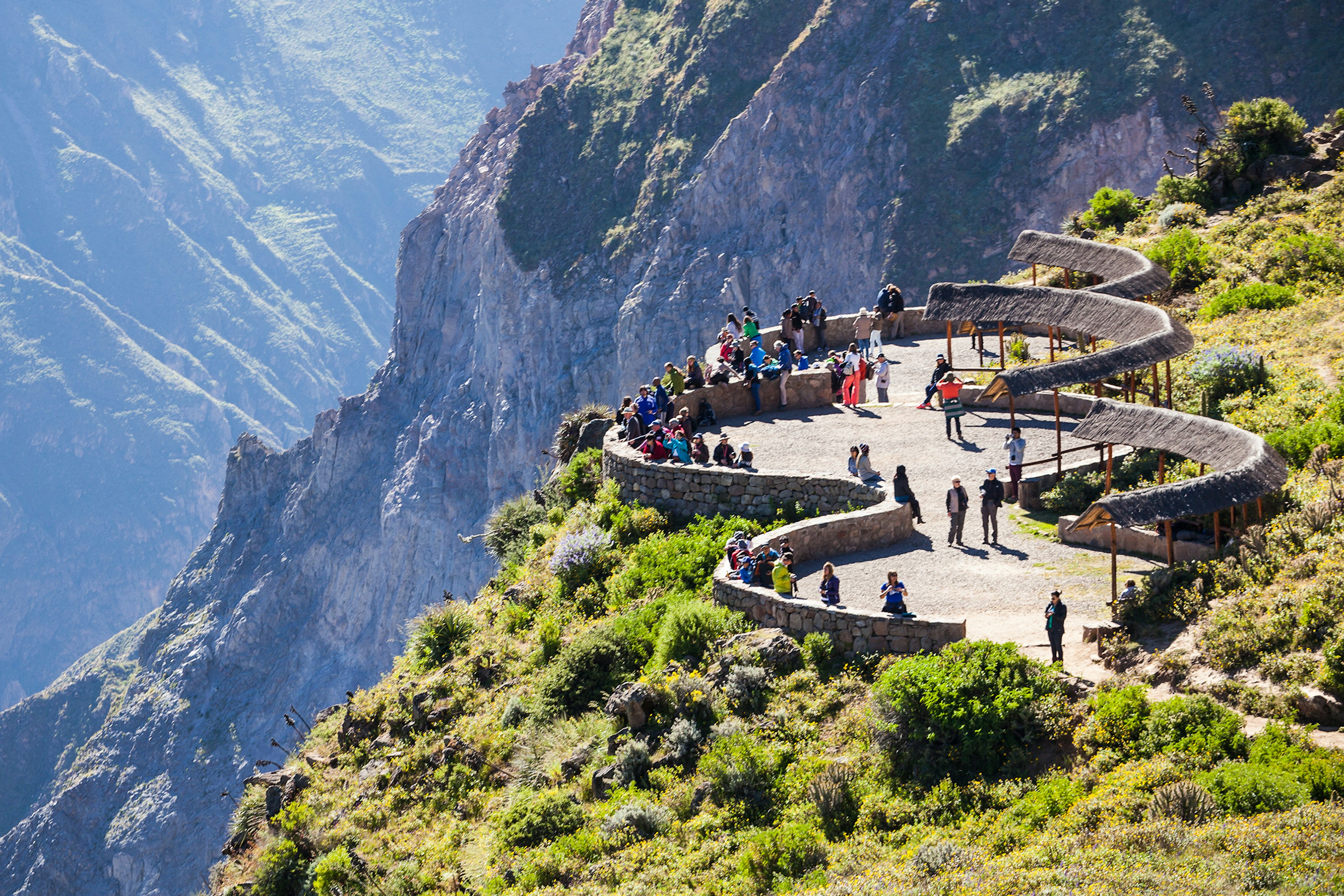 An aerial vide of people walk on a viewing platform overlooking a dramatic canyon