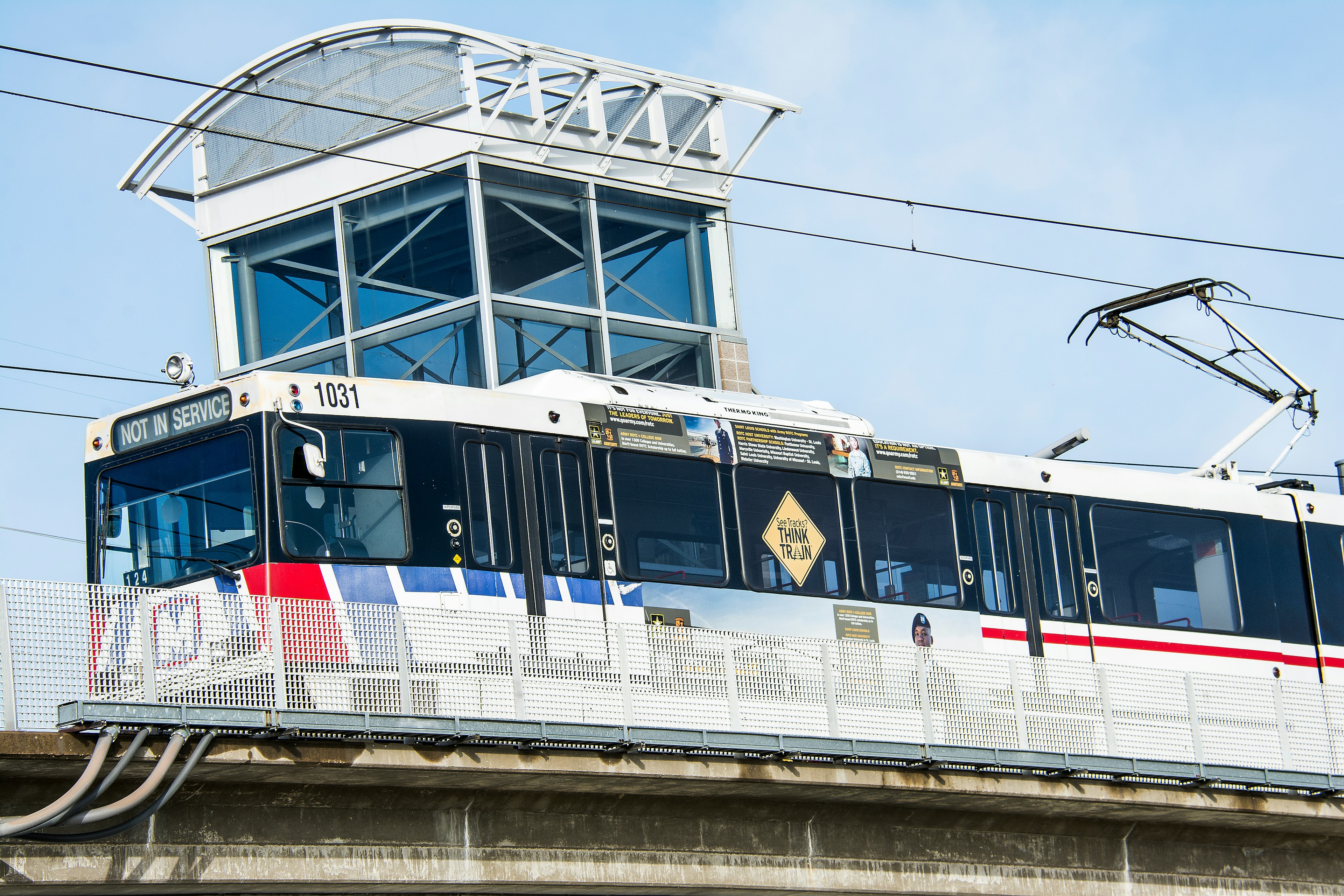 A red, white and blue commuter light rail train on an elevated track