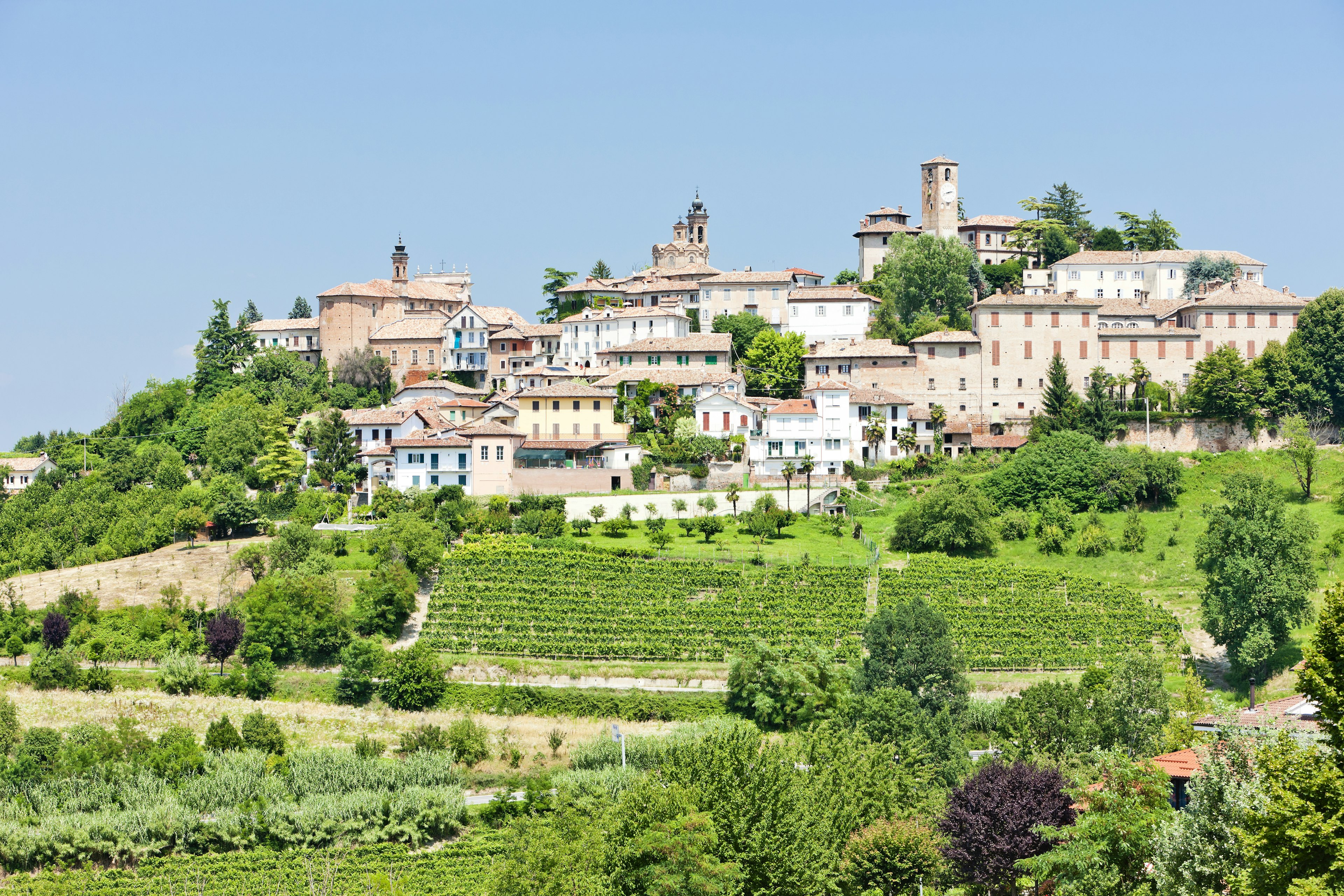 Whiteashed hilltop village of Neive surrounded by vineyards and rolling green hills