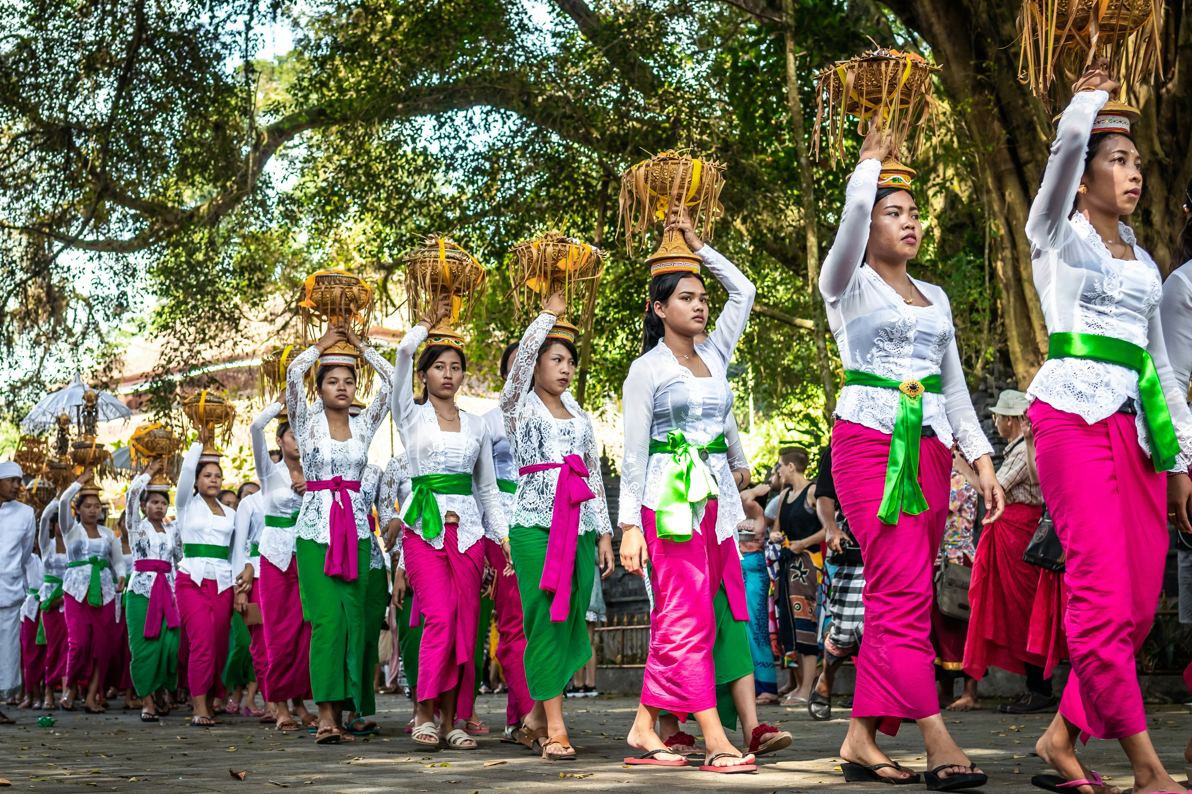 Balinese women in traditional dress carry offerings on their heads at a ceremony in Tirta Empul Temple.