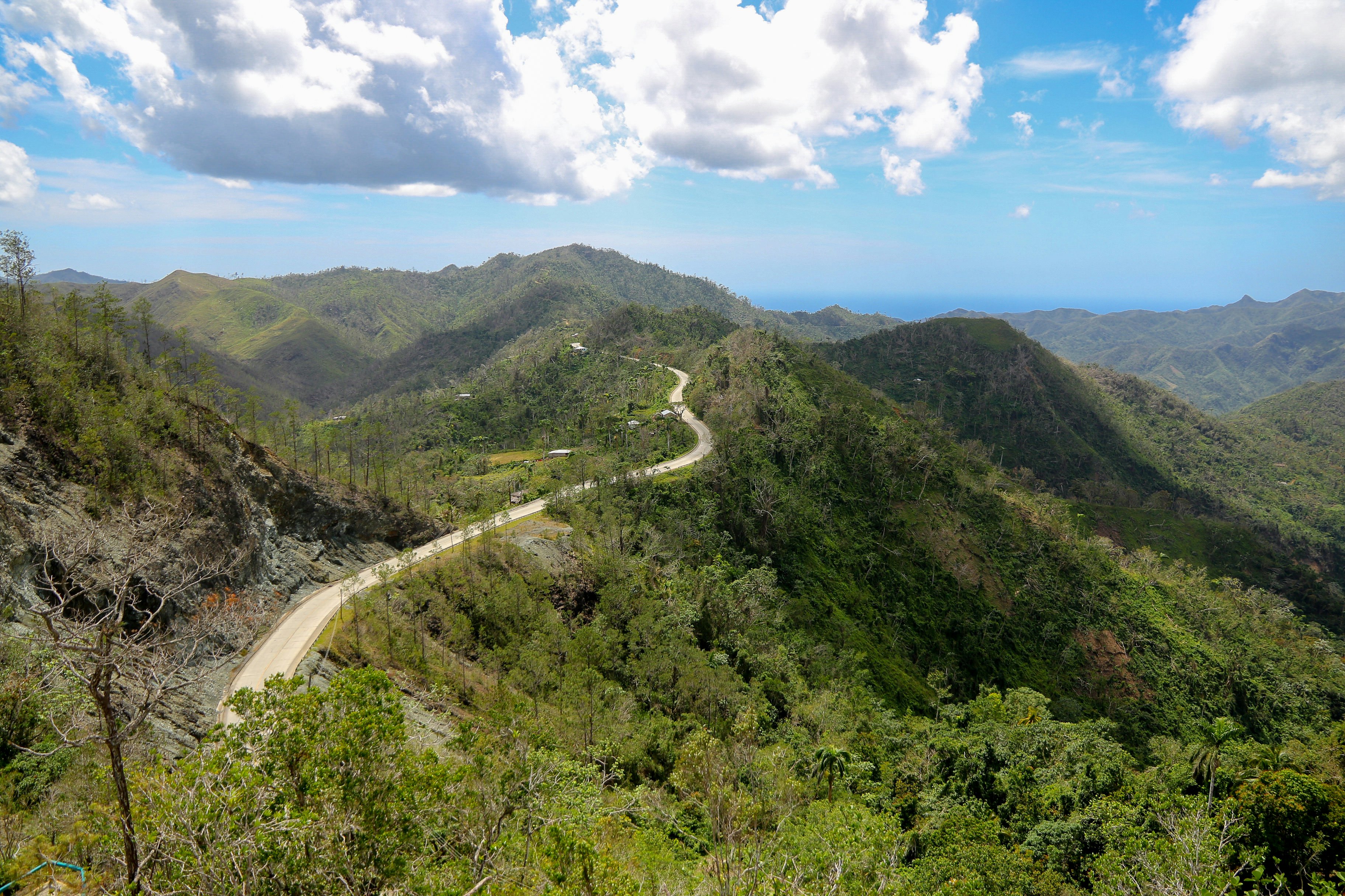 A winding road cuts across the top of green hills between Santiago and Baracoa in Cuba