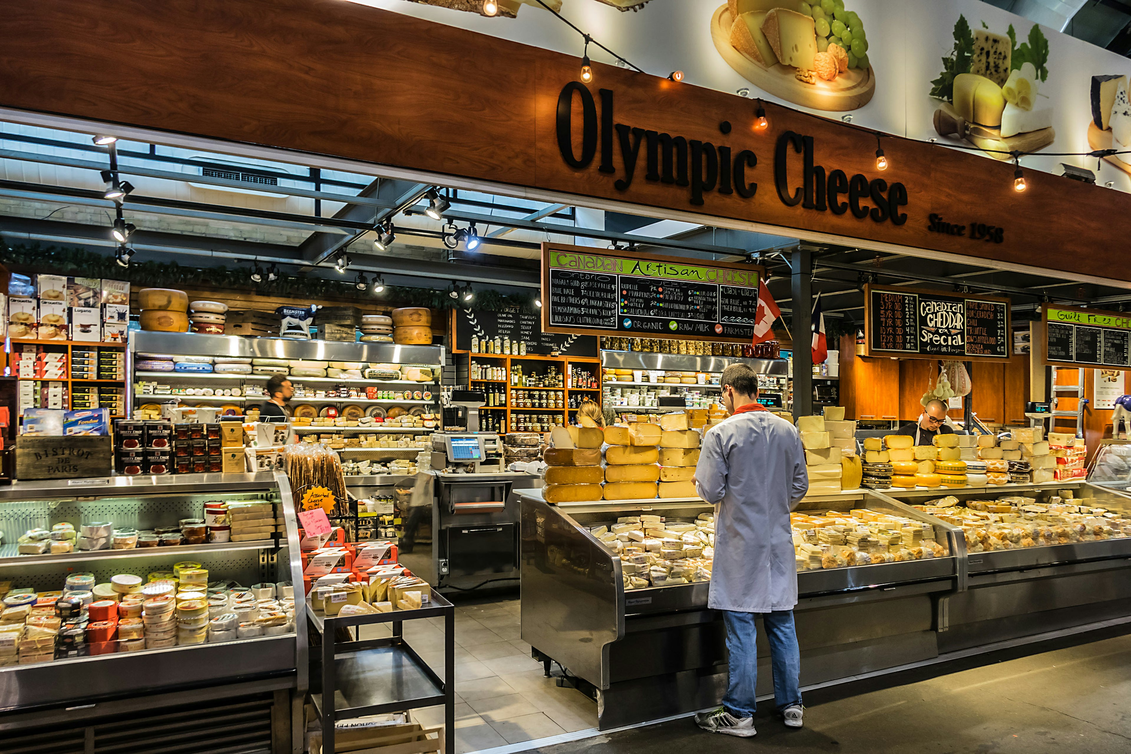 Man stands in front of the counter at Olympic Cheese stall inside St Lawrence Market in central Toronto.