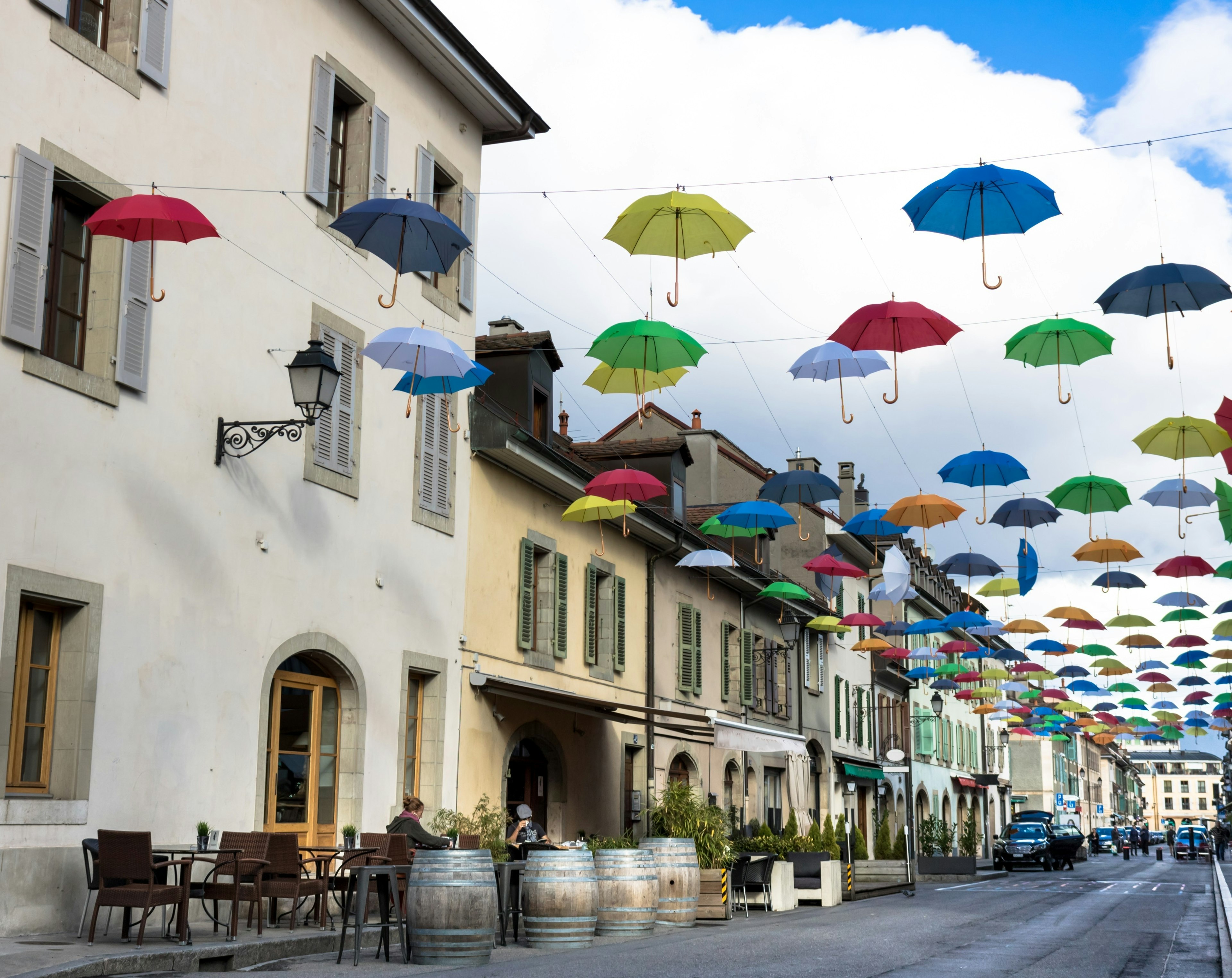 Multicolored umbrellas hang from wires above the street in the Carouge area of Geneva, Switzerland.