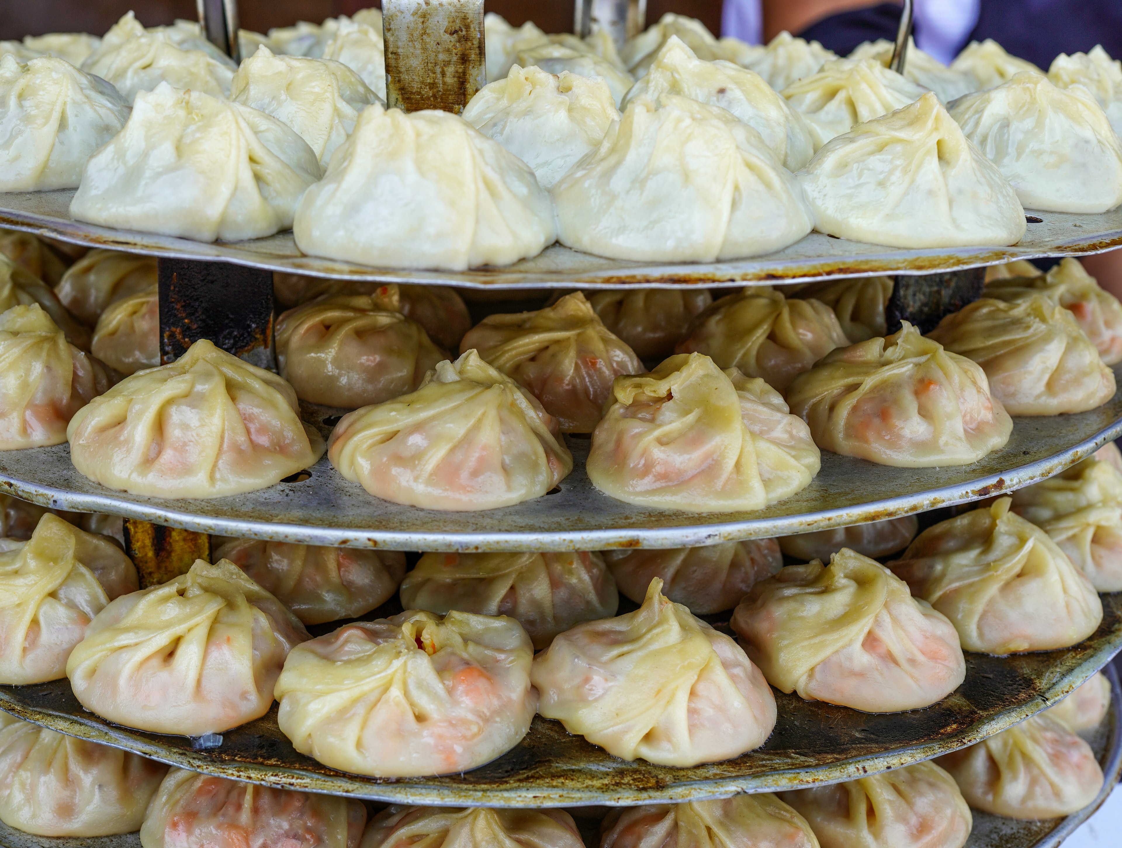 Tiered plates of small dumplings that have been pinched shut around an orange filling