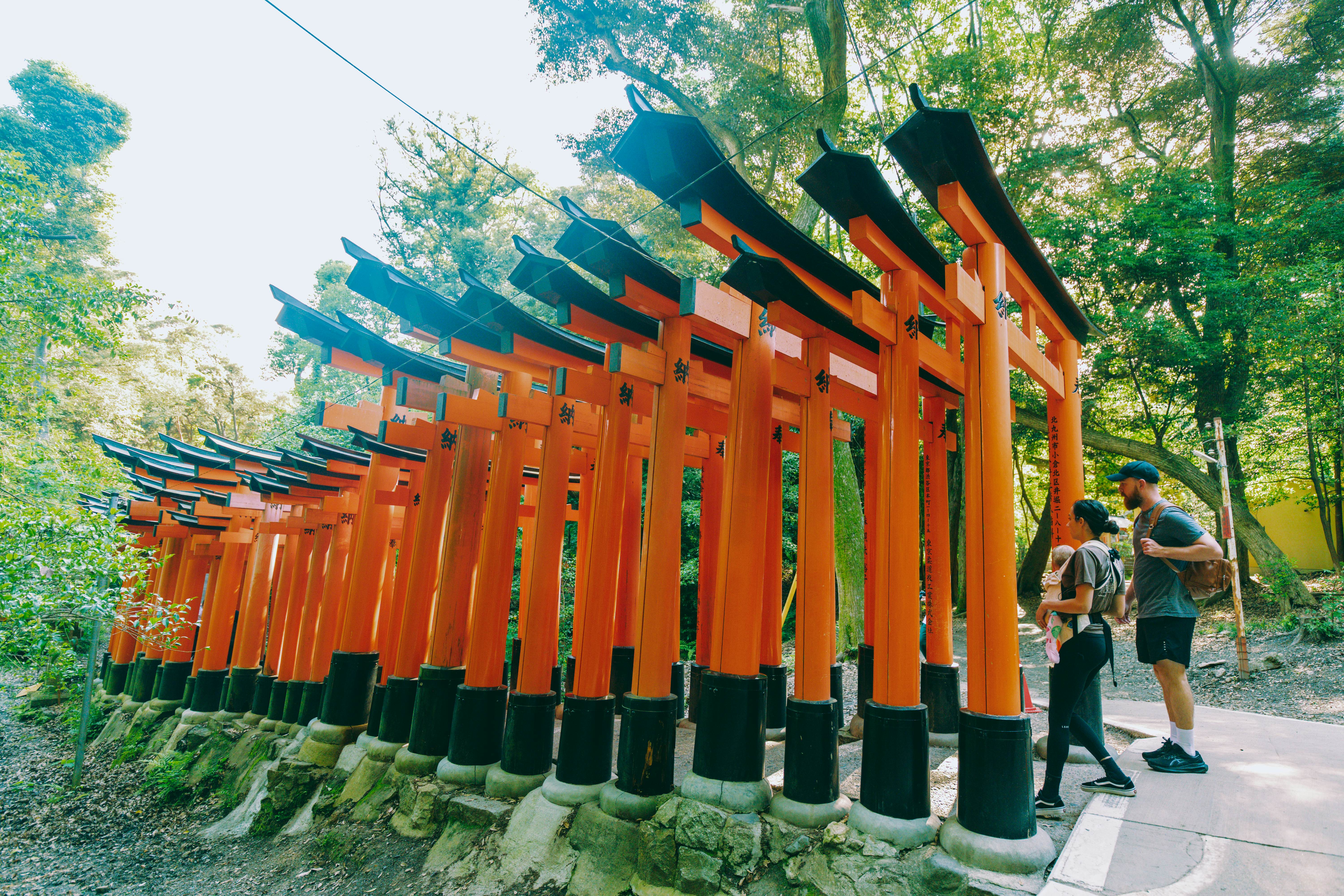 Visitors entering a section of orange gates at the Fushimi Inari-Taisha shrine in Kyoto, Japan