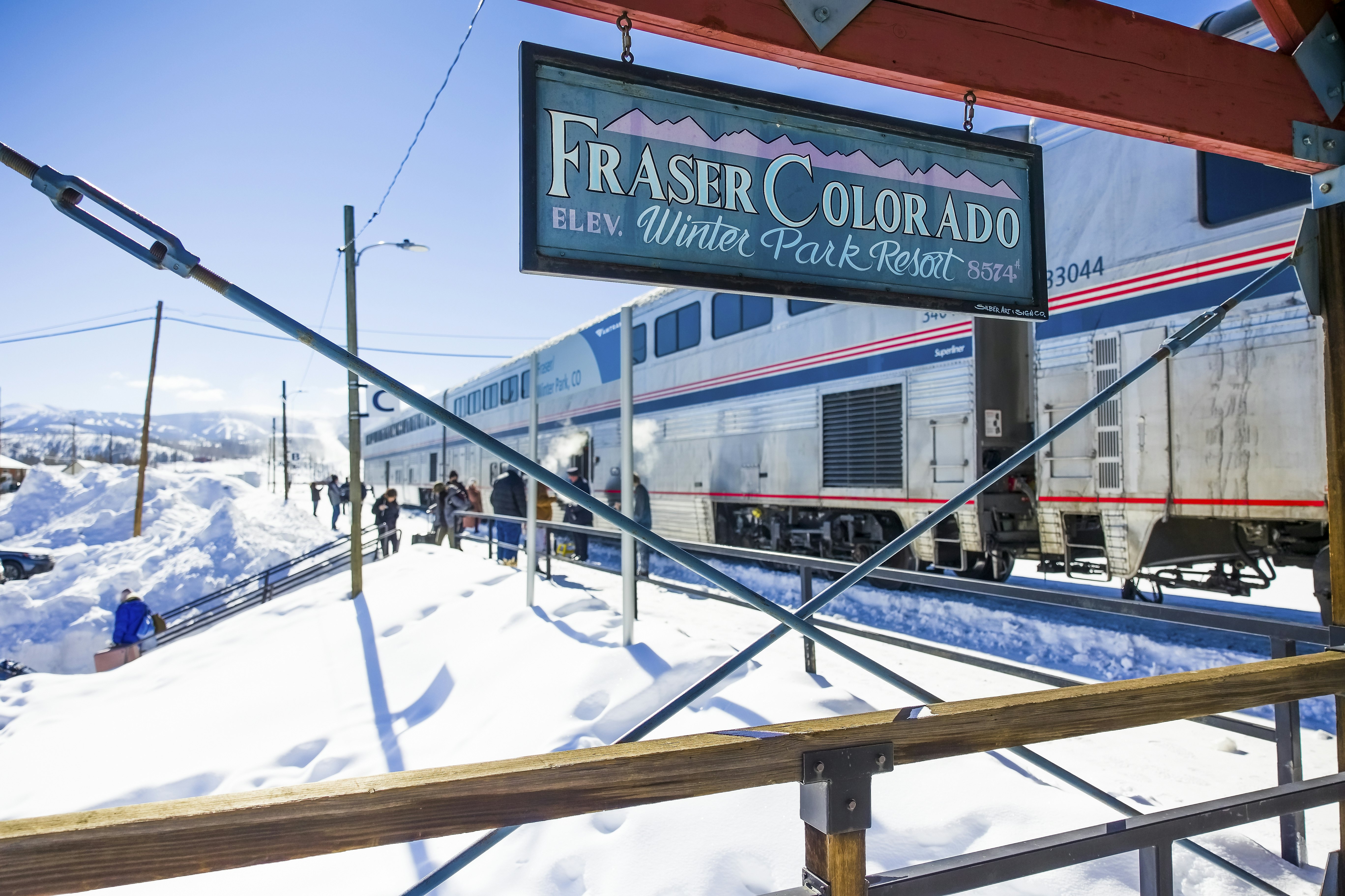 People board a large double-decker train that's stopped at a station on a cold snowy winter's day