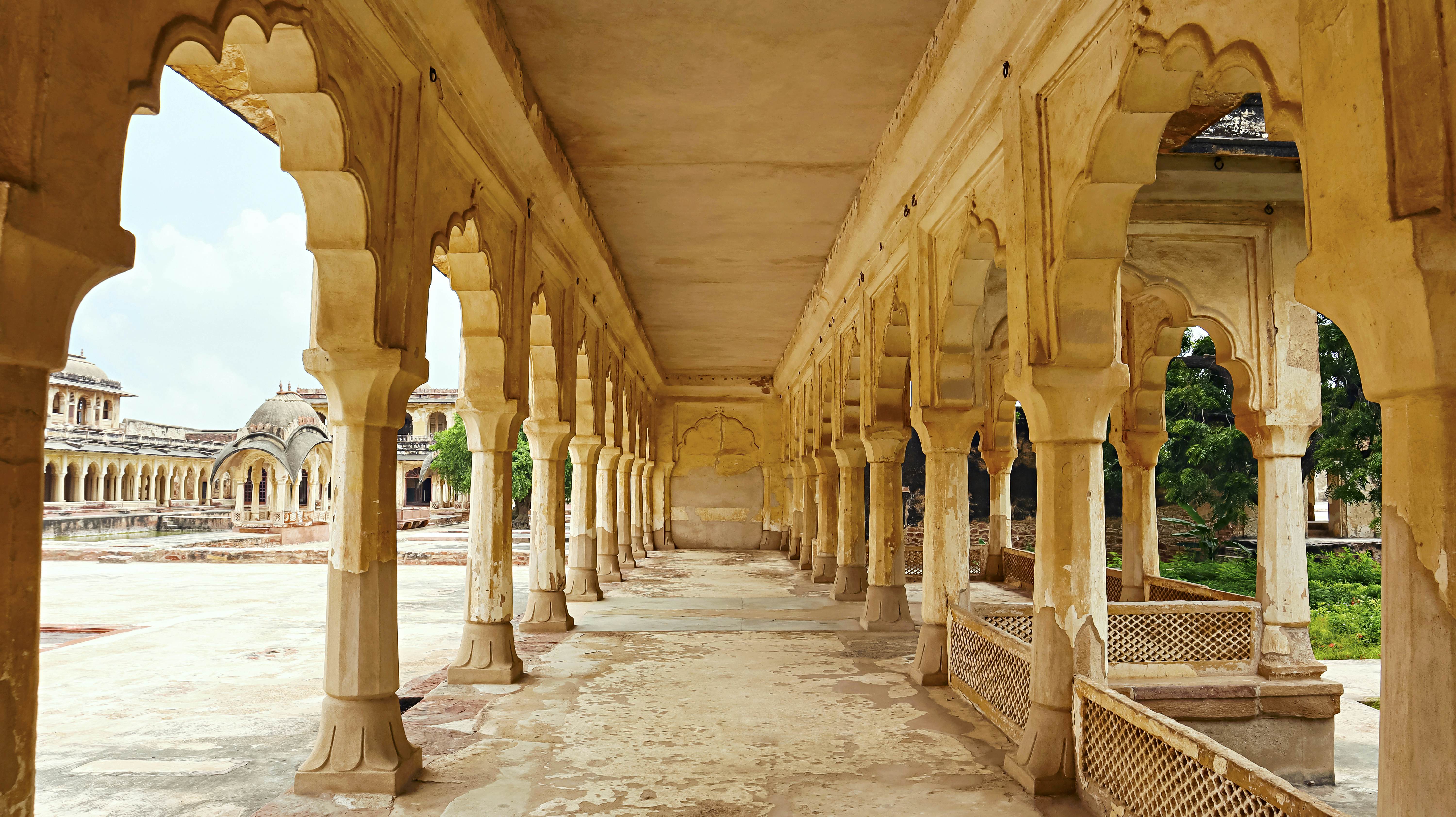 A covered walkway supported by columns in a landscaped garden