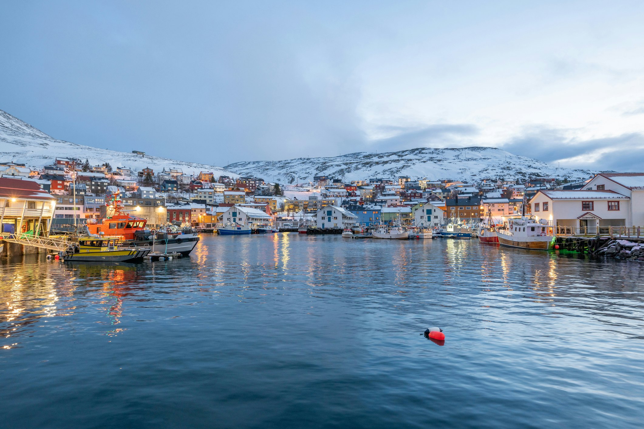 Boats moored in the snowy harbor at Honningsvåg, Norway.