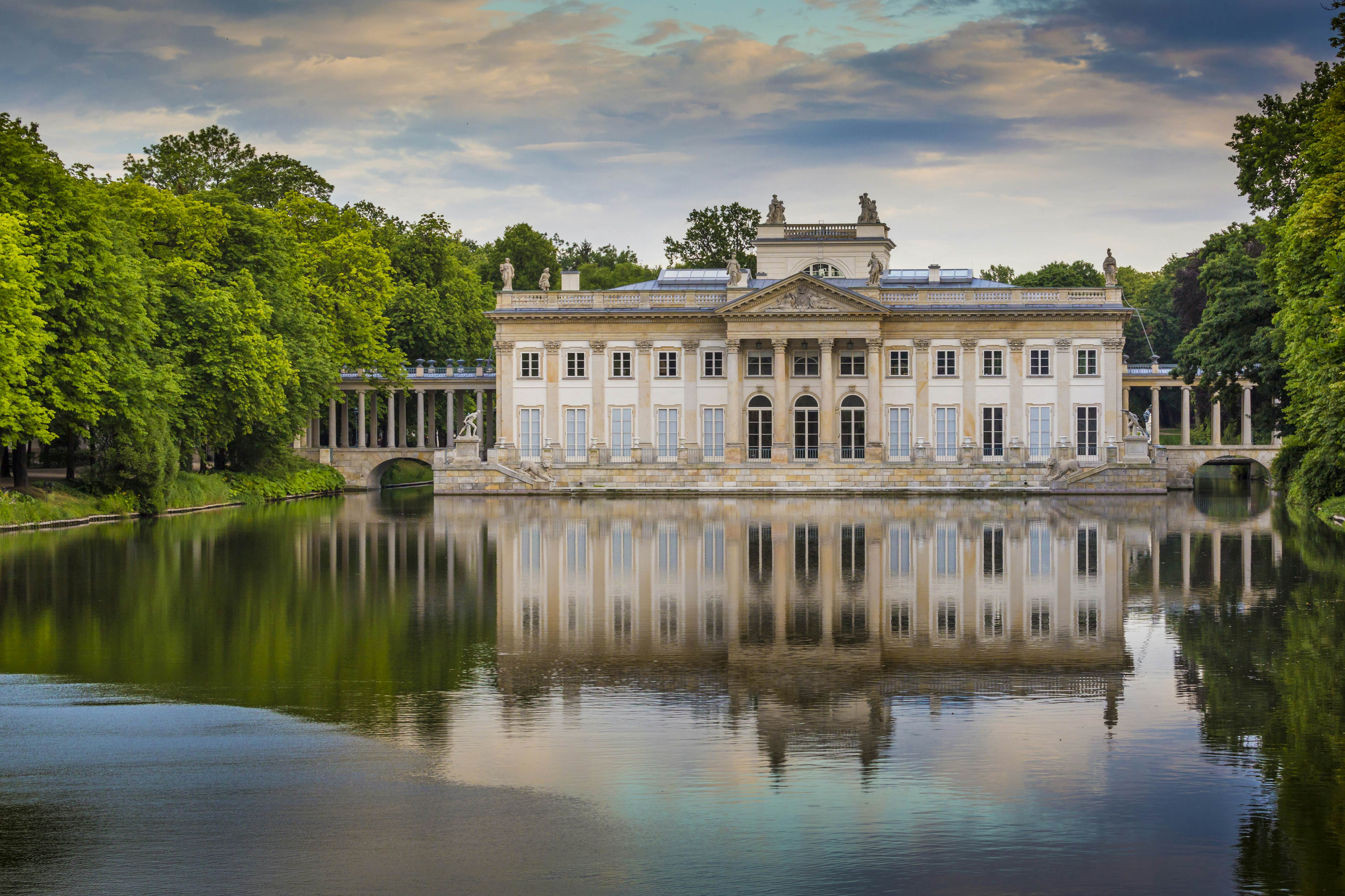 A large palace on the edge of a lake in parkland