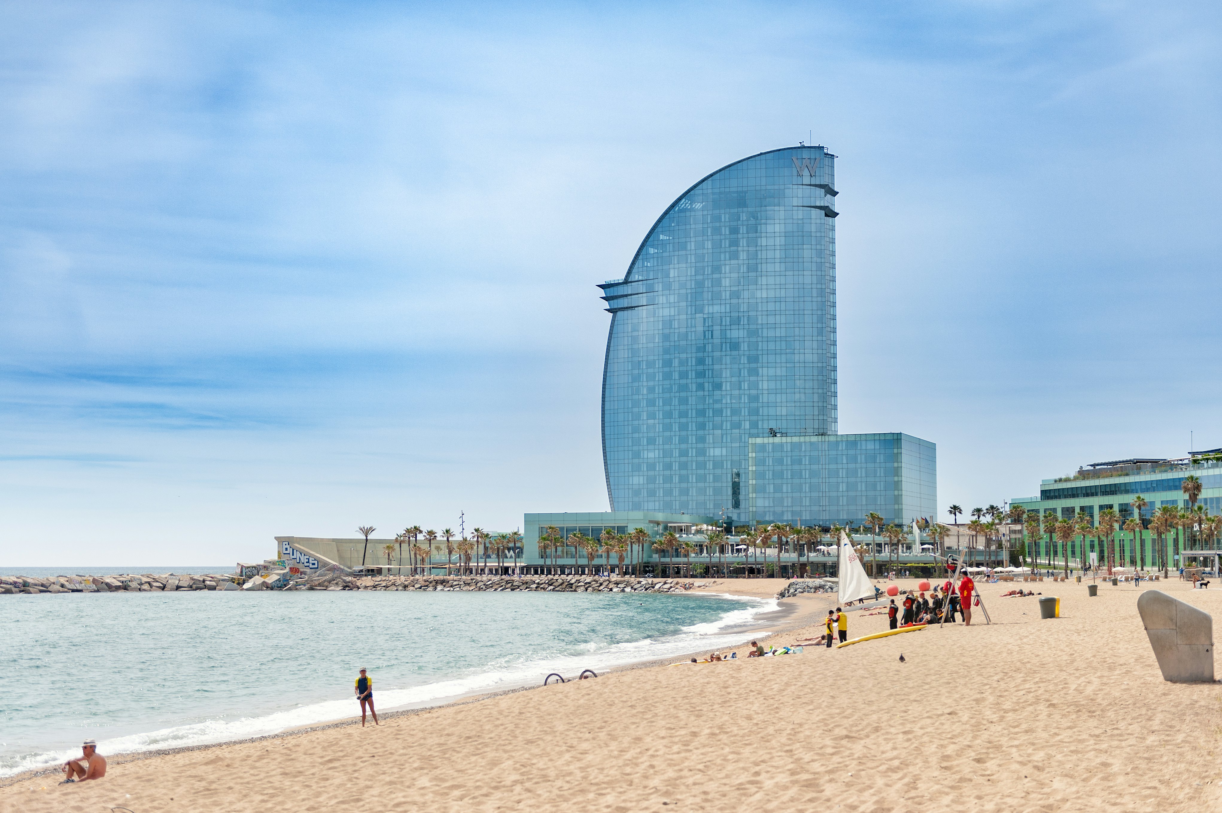 People on a sandy beach, with the W hotel in the background, in Barcelona, Spain