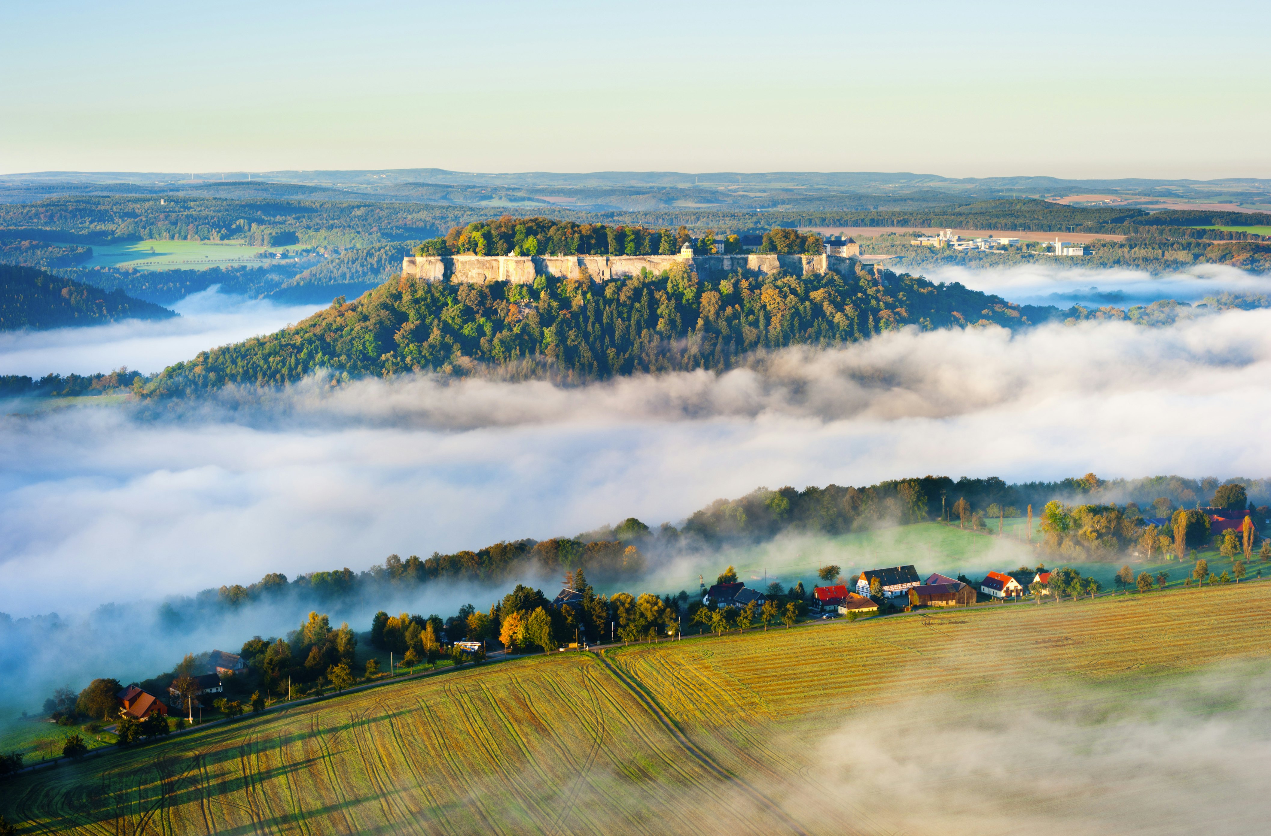 Festung Konigstein Castle rises over misty fields in Saxony, Germany.