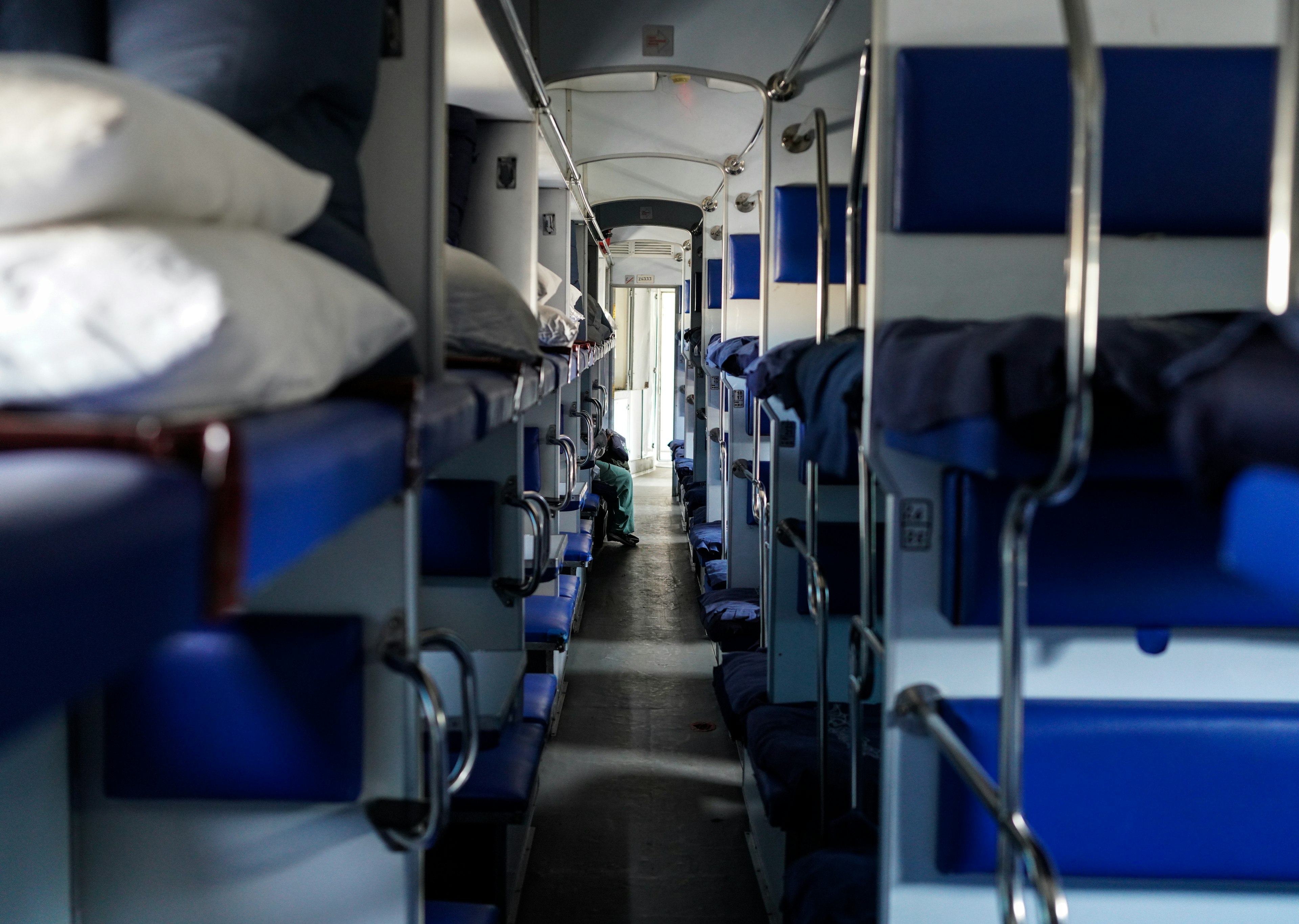 A train corridor with bunk beds and benches on either side