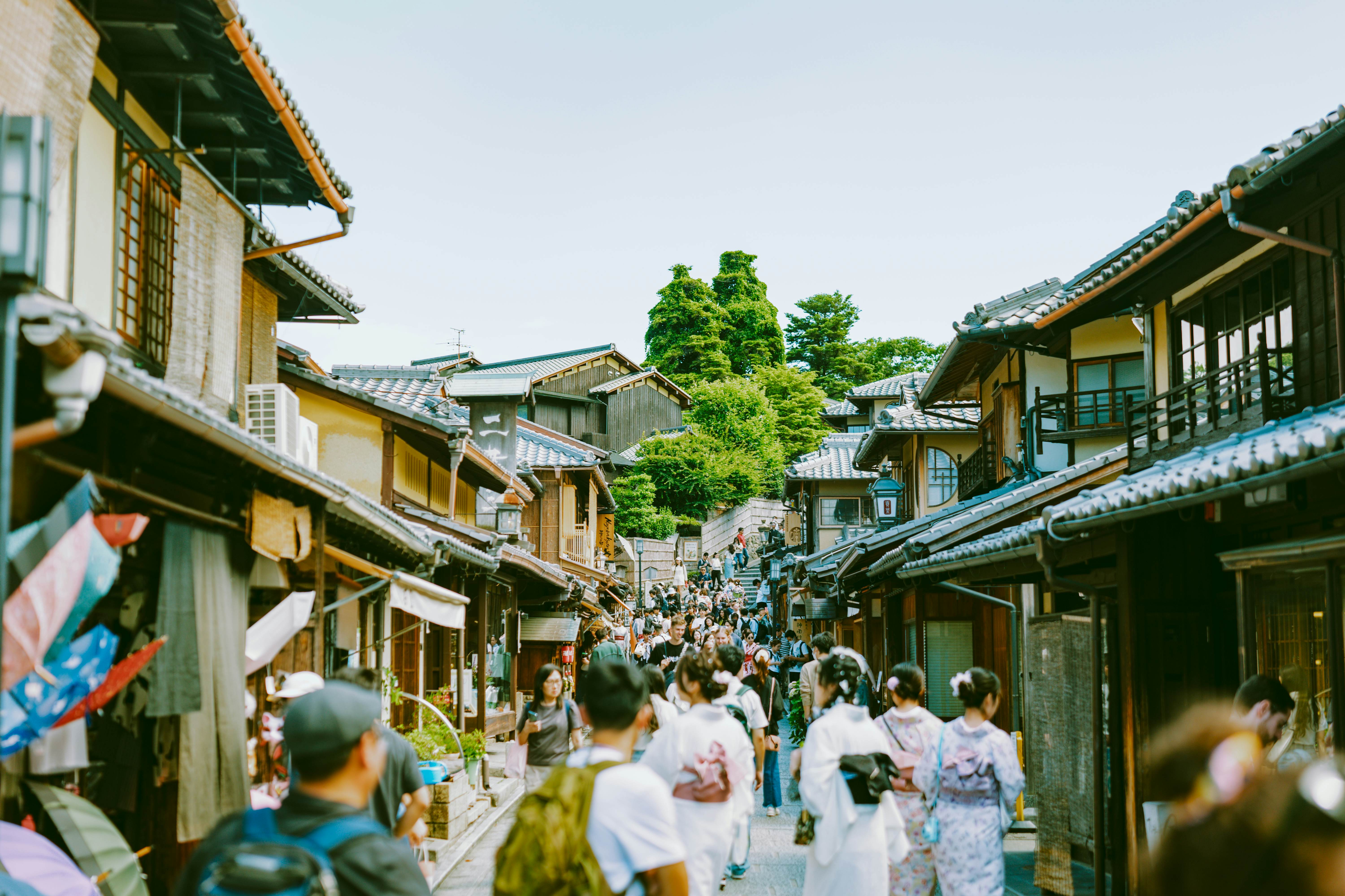 People walk down a pedestrian street lined with traditional wooden Japanese houses