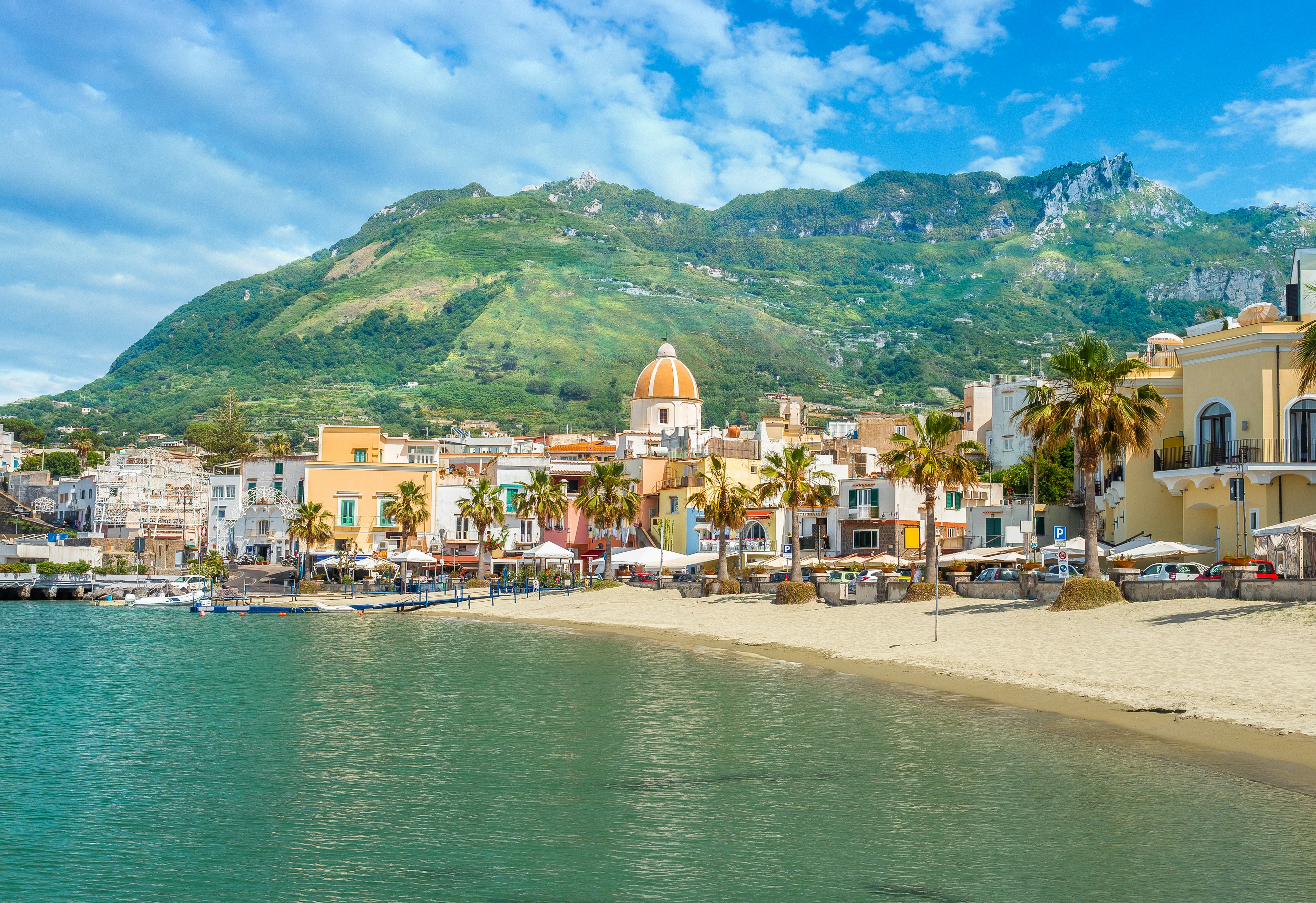 Beach in Forio with green hills in the background.