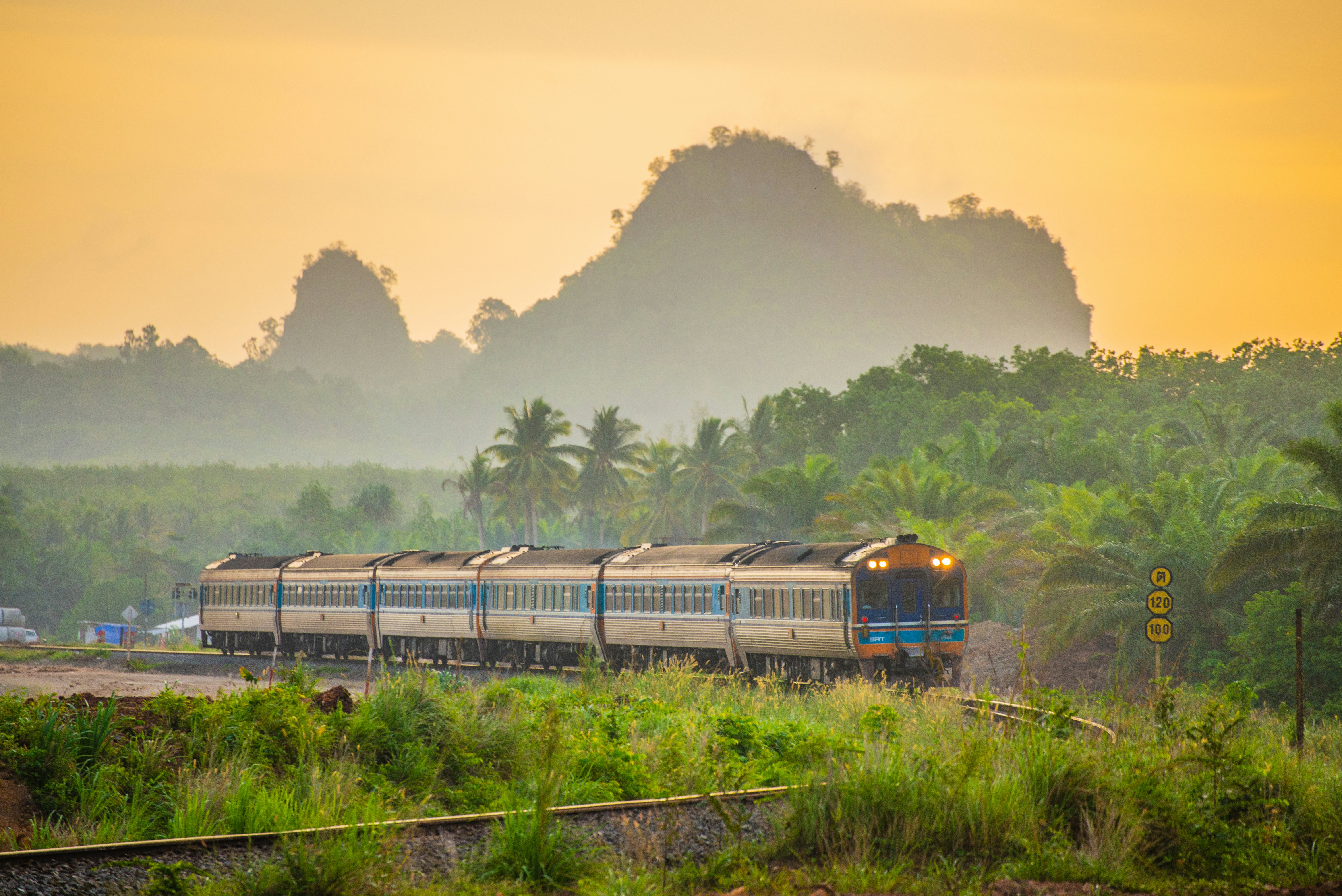 A train passes mountains in Thailand.