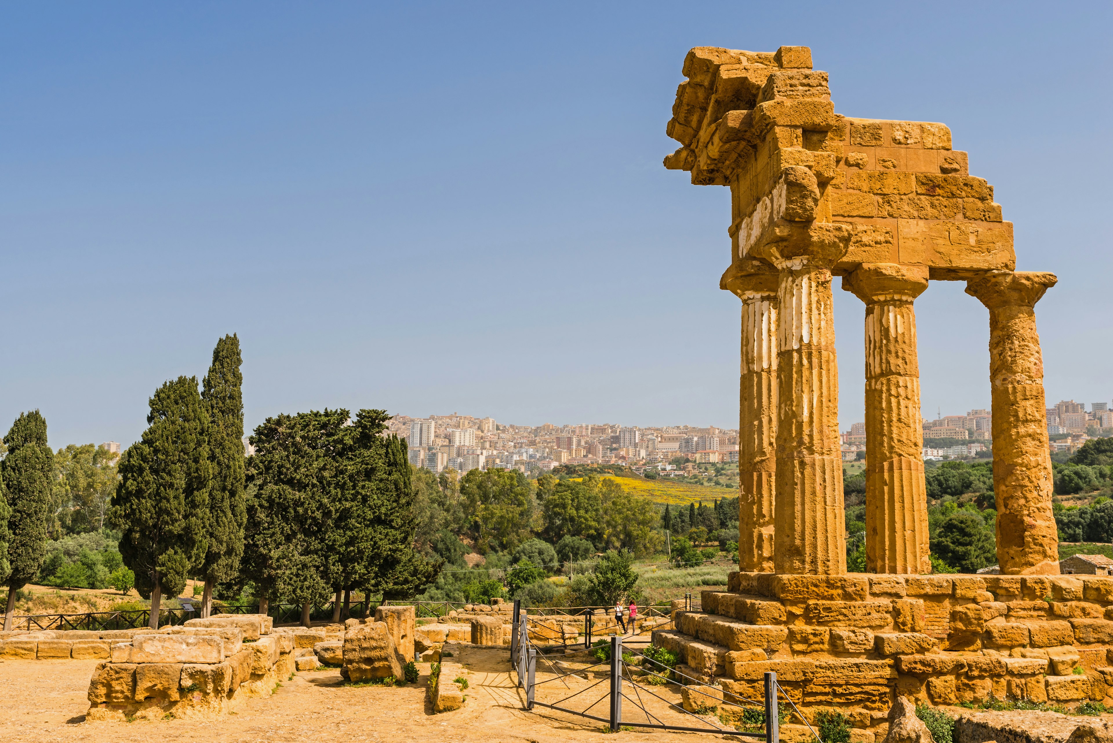 Ruins of an ancient temple, Temple of Dioscuri (Castor and Pollux), with the modern buildings of a town in the distance