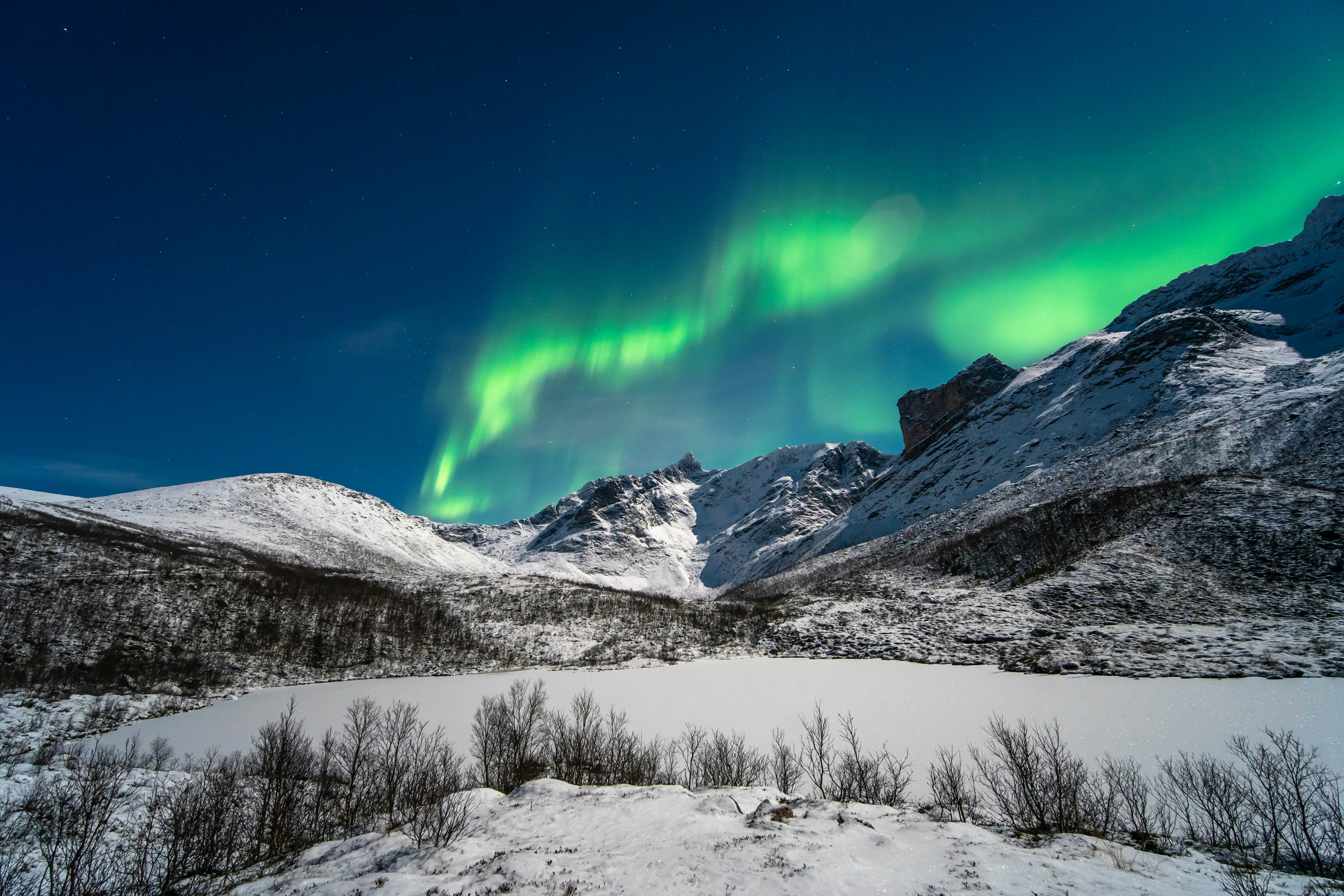 The northern lights over snowy hills in Tromsø, Norway.