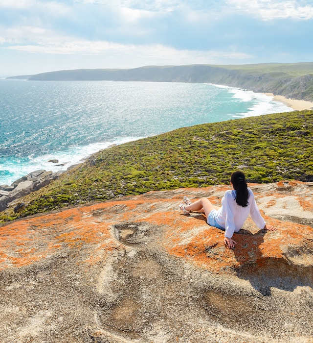 Woman enjoying the scenery while sitting on the edge of the cliff at Remarkable Rocks, Kangaroo Island, South Australia License Type: media Download Time: 2023-08-21T07:29:02.000Z User: lonelyplanetmedia Is Editorial: No purchase_order: